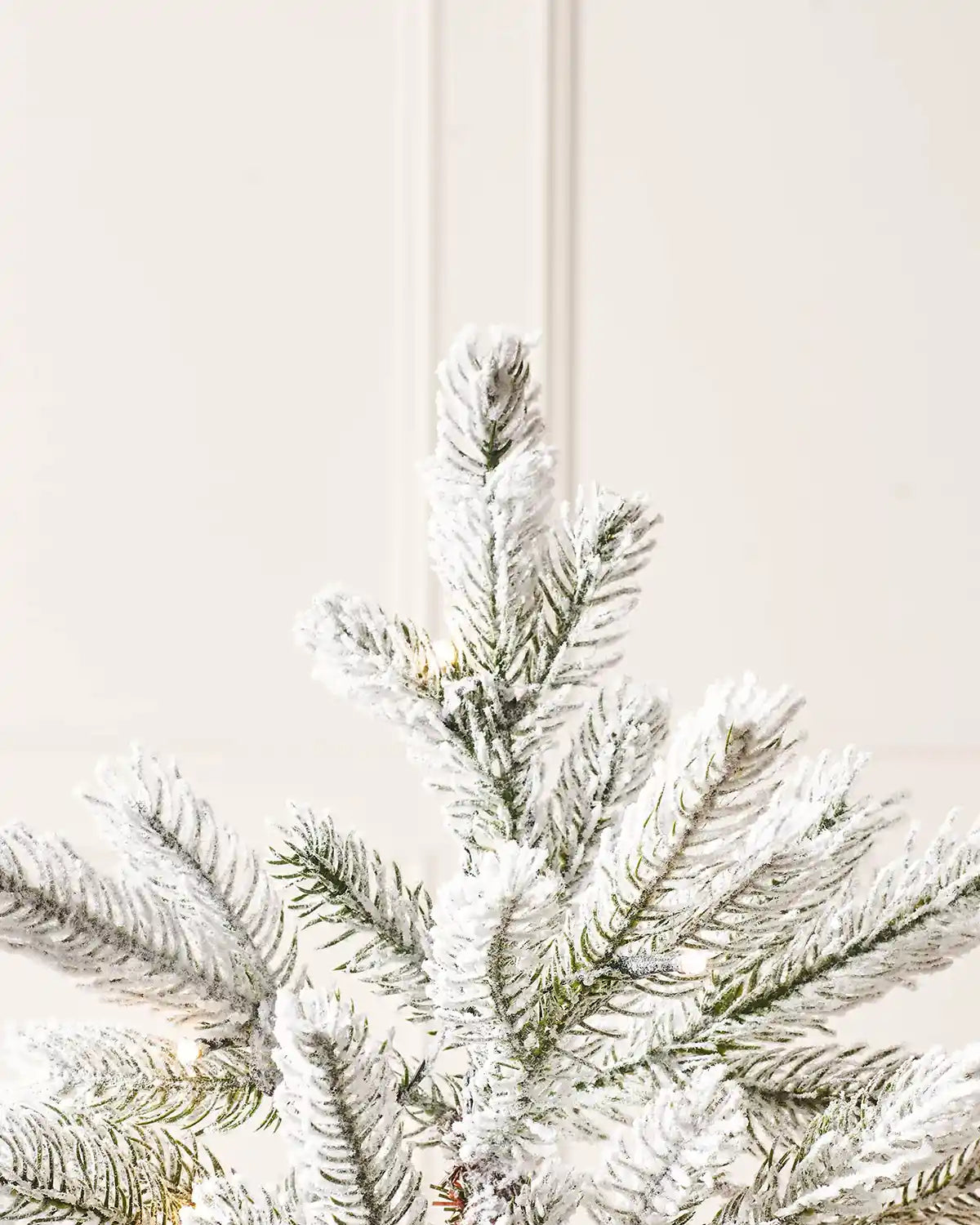 Top section of a 4 ft snow flocked potted Christmas tree with frosted branches and pre-lit LEDs