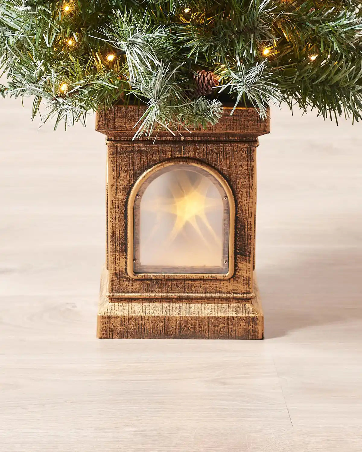 Close-up of the decorative rustic-style pot with a glowing star window at the base of the tree
