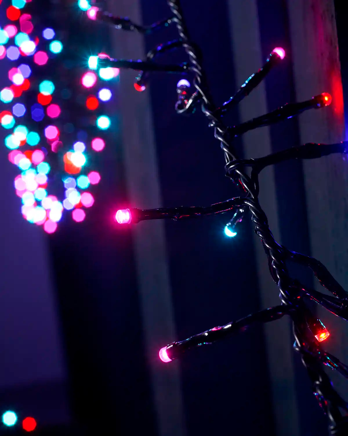 Detail view of aurora cluster LEDs on black cable against a dark fence.