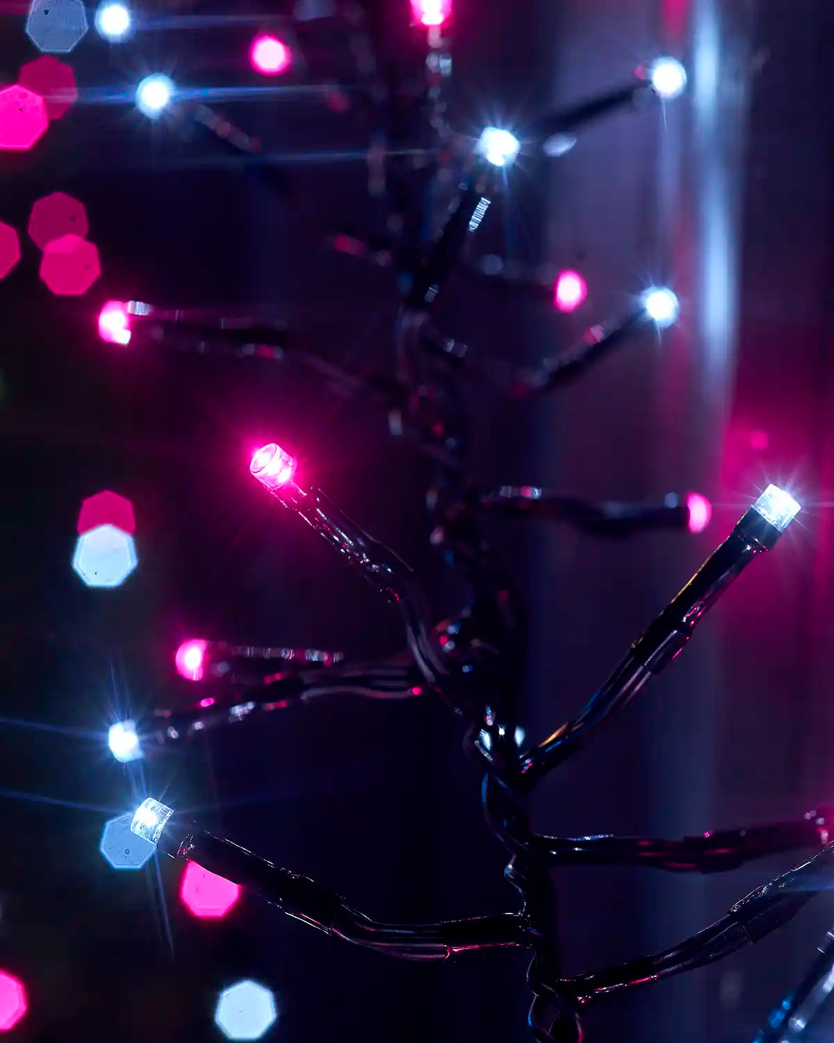 Close-up of pink and white LEDs on black cable against a dark background.