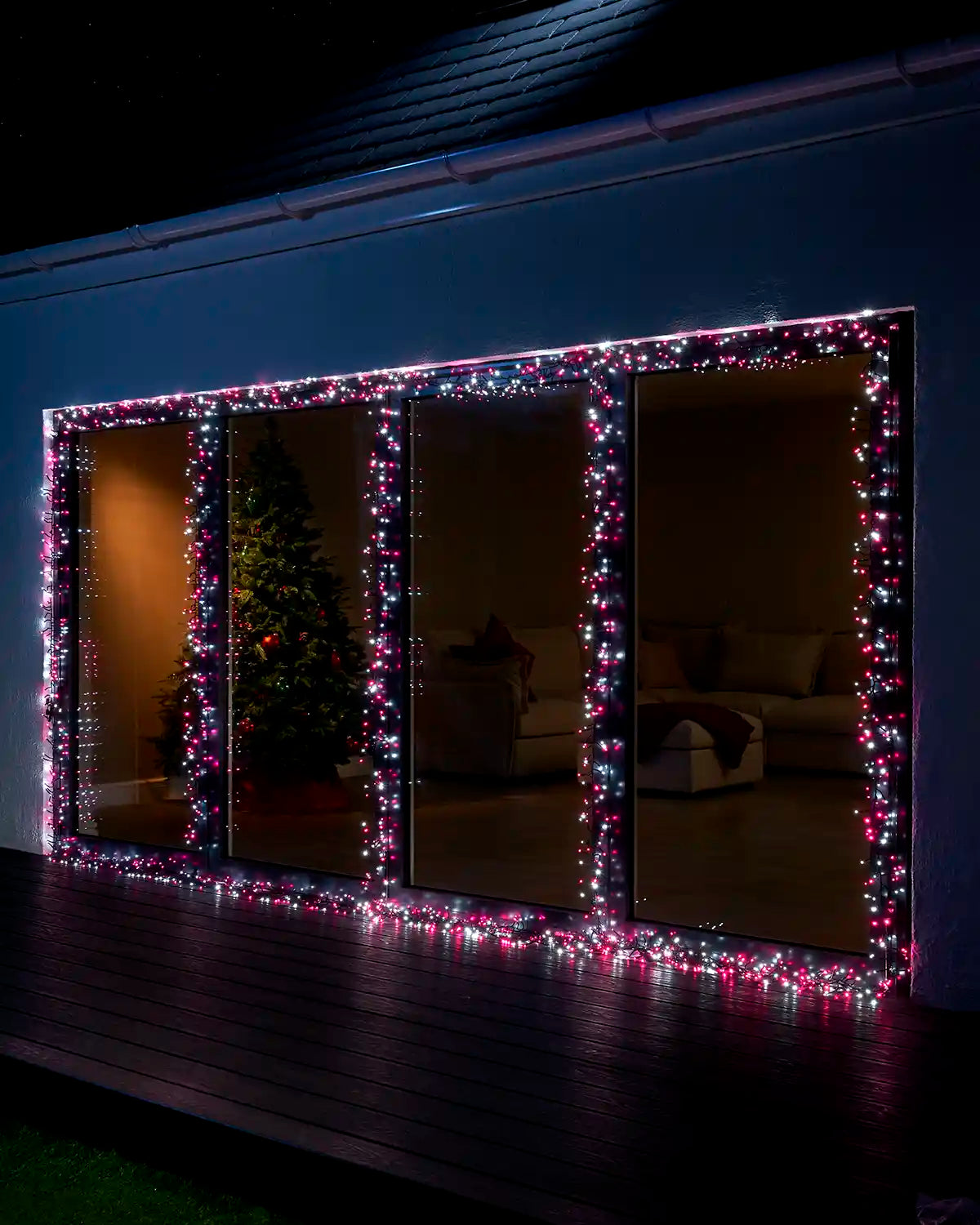 Pink and white cluster lights displayed around large outdoor window frames at night.