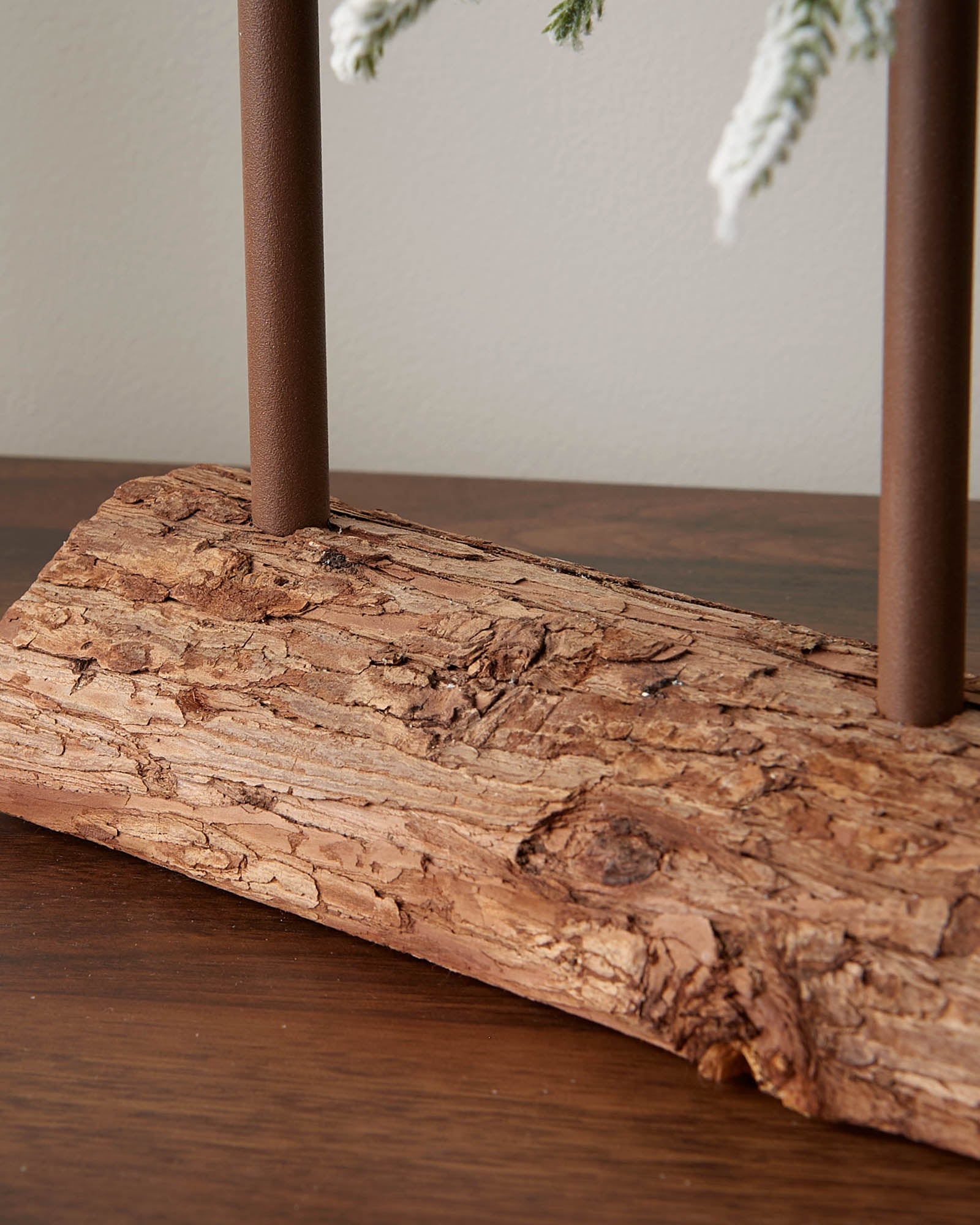 Close-up of the textured natural-look log base on the snow-flocked tree trio.