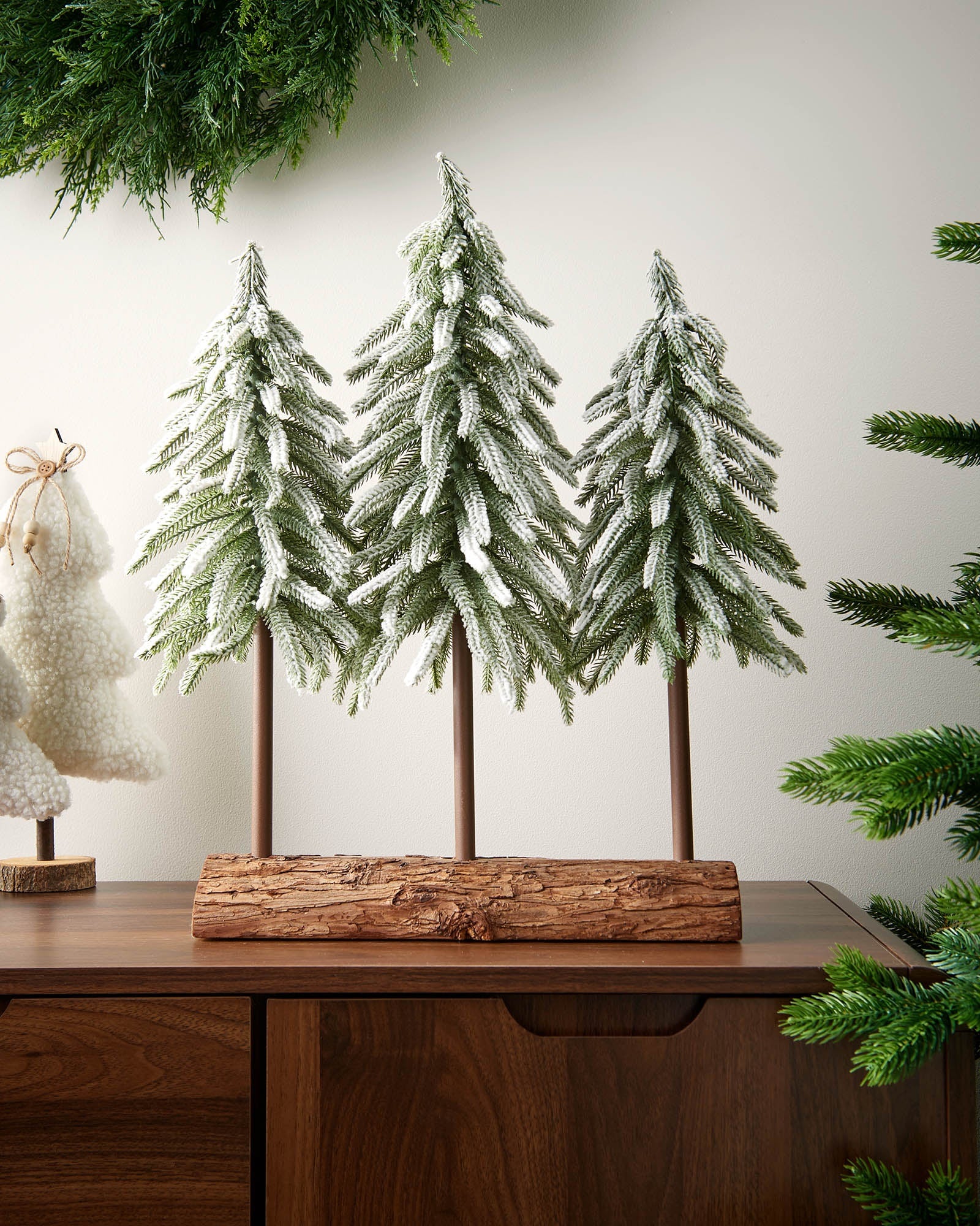Snow-flocked 50cm tree trio displayed on a tabletop with a natural-look log base.