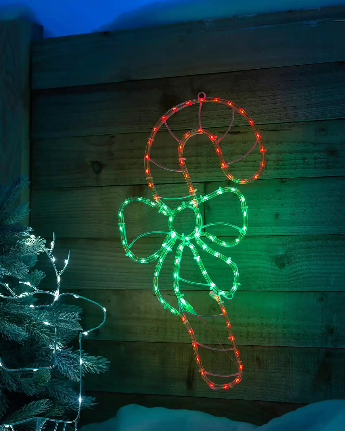 51 cm pre-lit candy cane rope light glowing in an outdoor Christmas scene