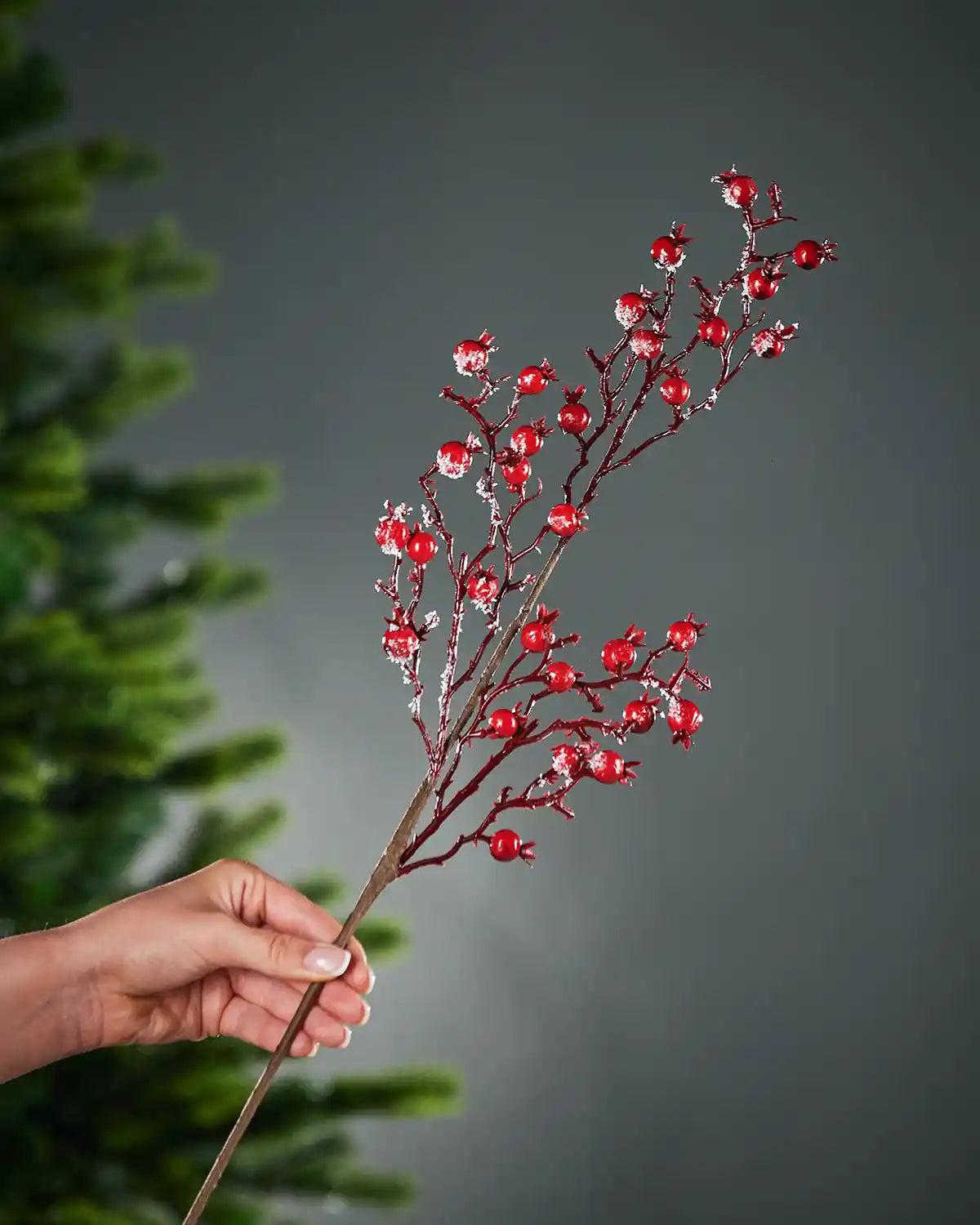 57 cm red artificial berries tree pick held beside a Christmas tree