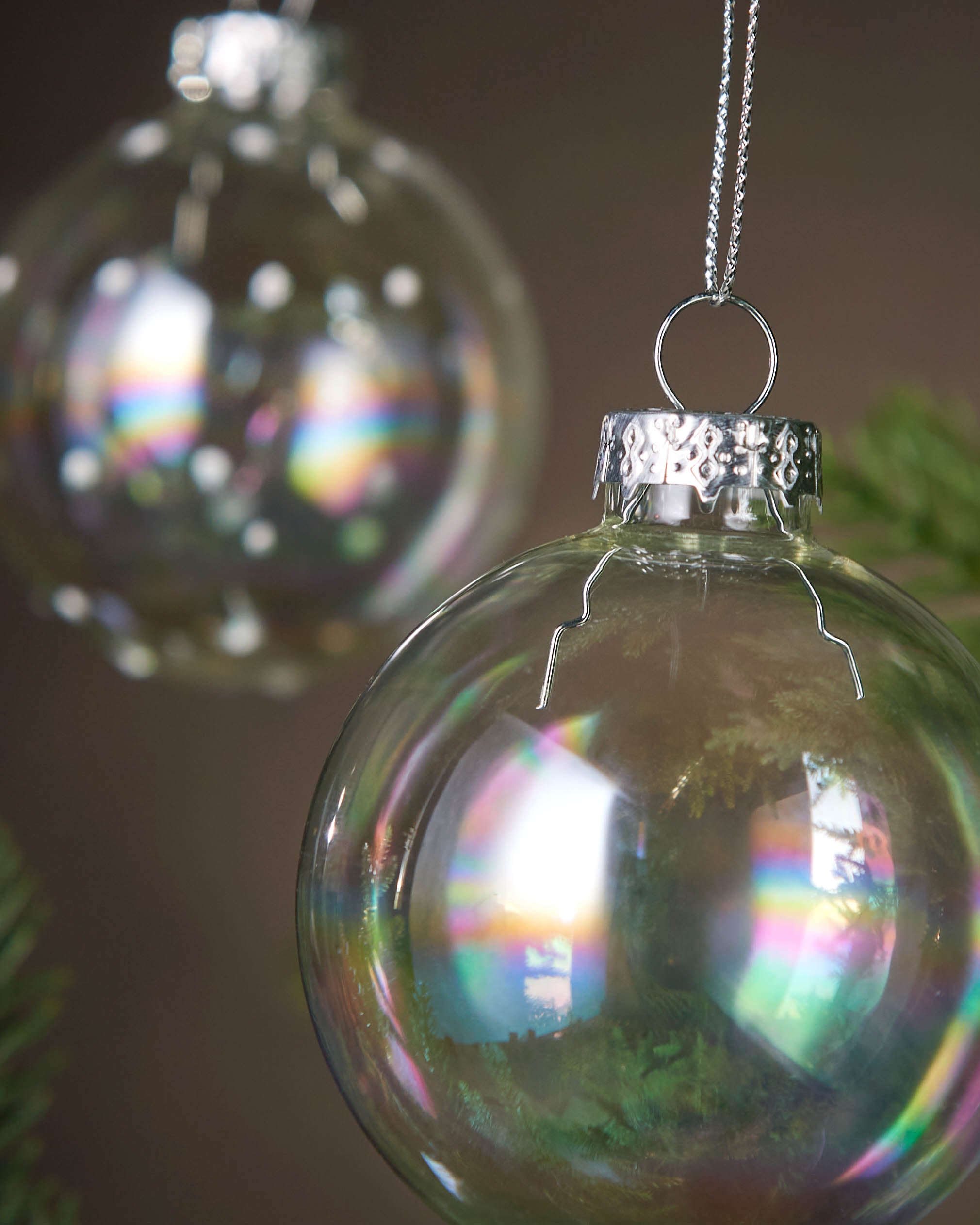 Decorative glass ornaments hanging on a Christmas tree with a dark 