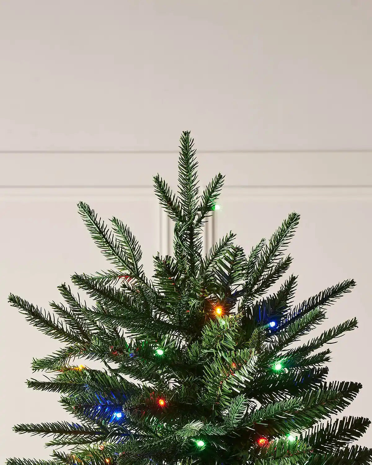 Top branch detail of 5ft Grand Alaskan Fir Christmas tree with green fir foliage and multicolour LED Christmas lights