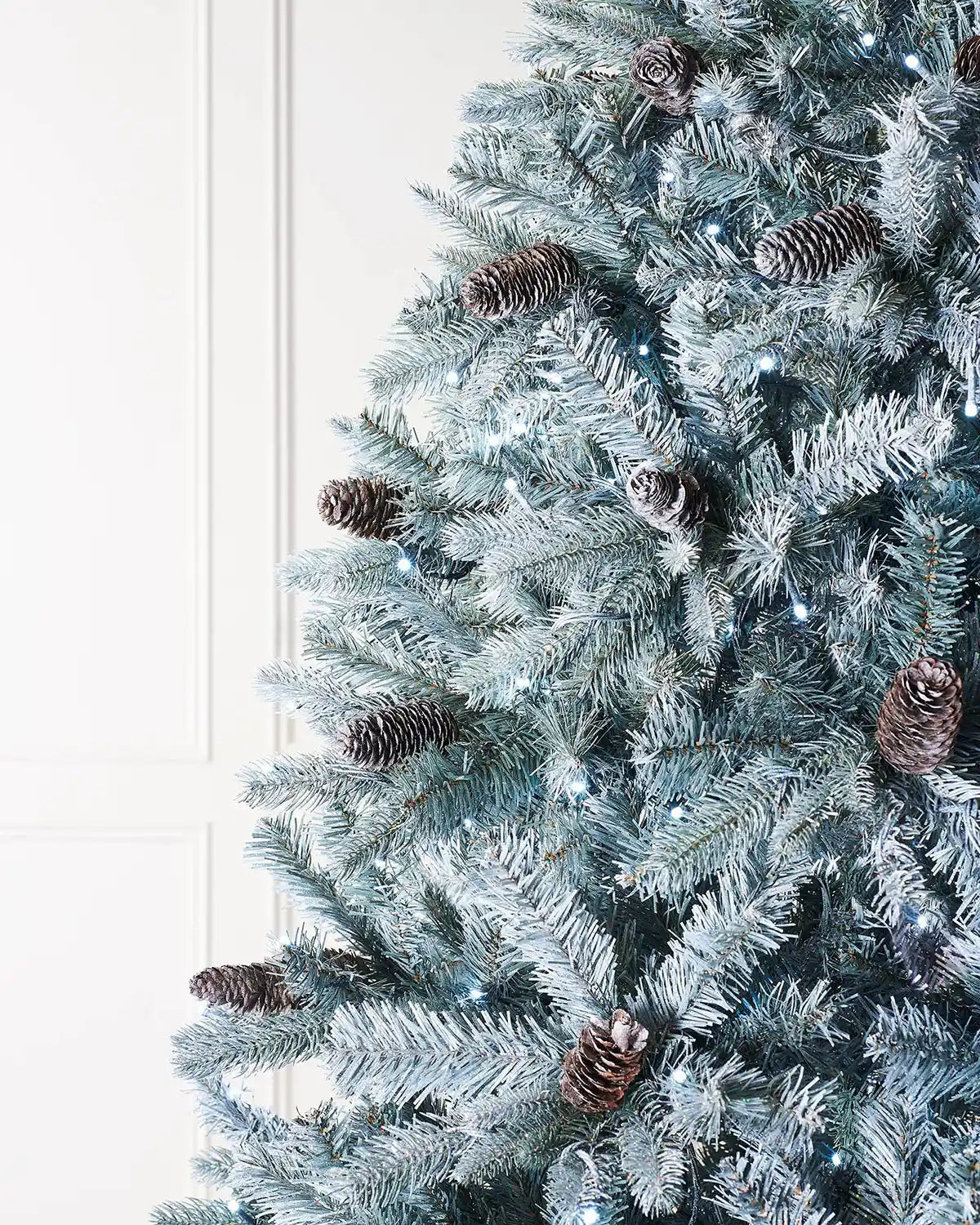 Close-up of frosted Edwardian spruce branches with pinecones and bright white LED lights
