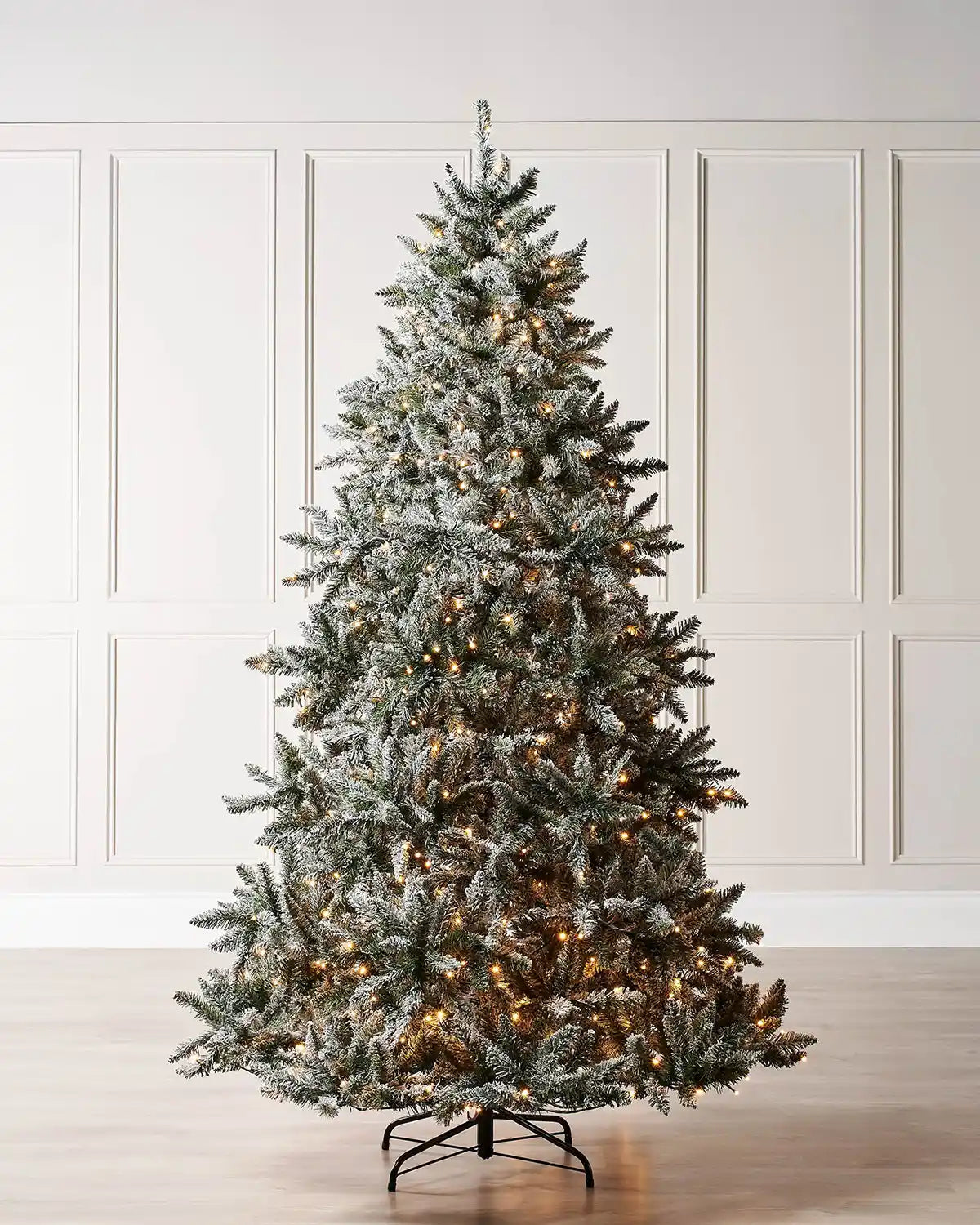 Pre-lit 5 ft full bodied snow flocked Christmas tree displayed indoors with warm white LEDs and a full snow-dusted silhouette