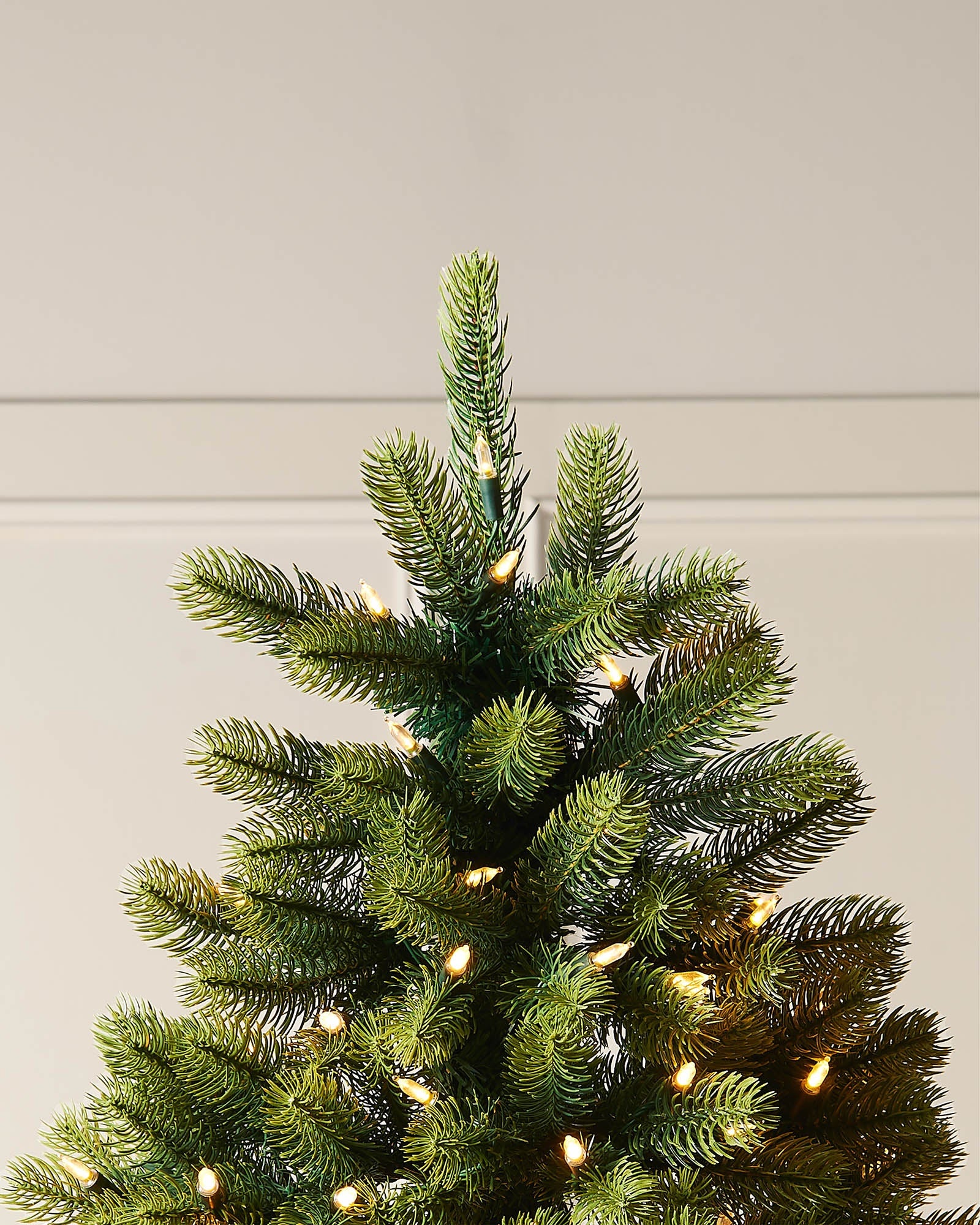 Top section of the 5ft pre-lit mixed pine half Christmas tree with shaped branches and warm white lights.