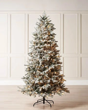Pre-lit 5 ft slim snow flocked Christmas tree displayed indoors with warm white LEDs and a narrow snowy silhouette