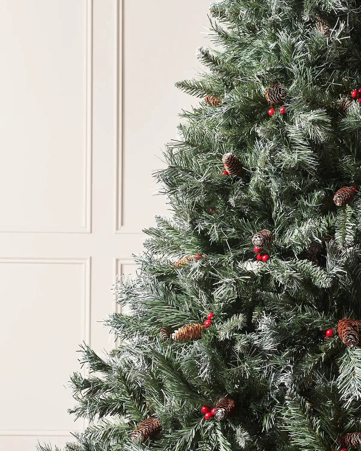 Close-up of a 5 ft Scandinavian blue spruce Christmas tree with frosted branches, pinecones and red berries