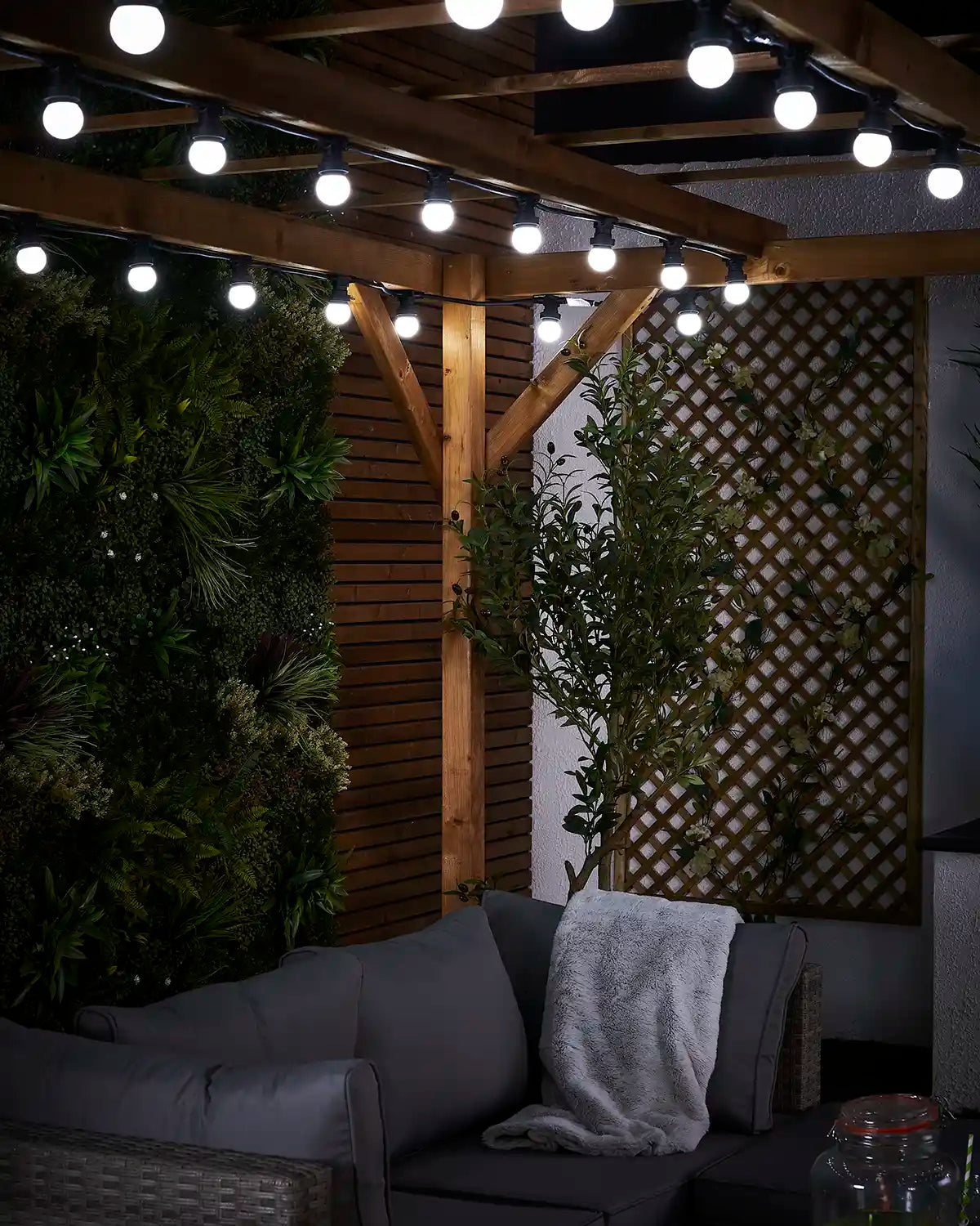 Close-up of white E27 festoon bulbs hanging from a black cable under wooden beams.