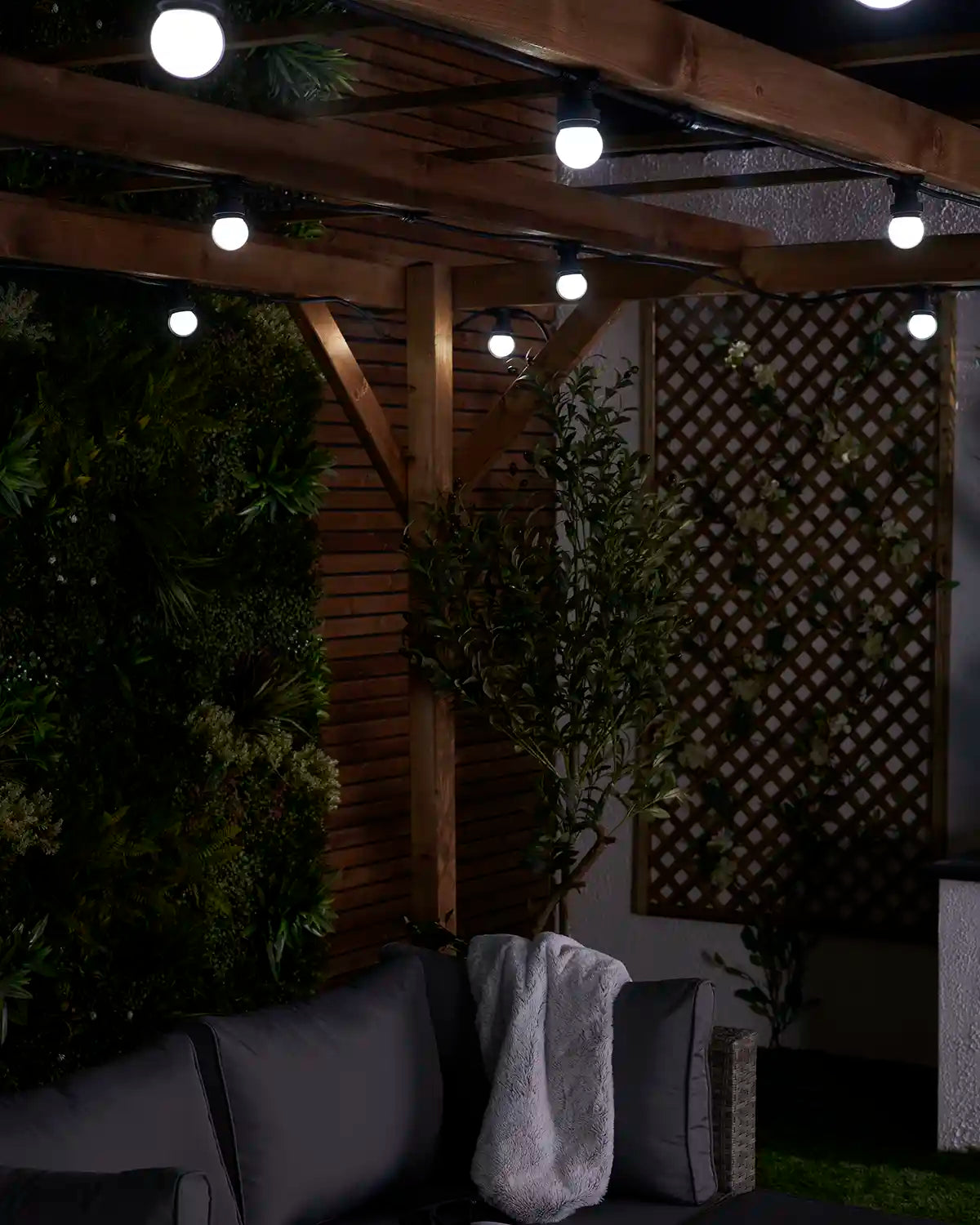 White E27 festoon bulbs displayed on a black cable beneath a wooden pergola.