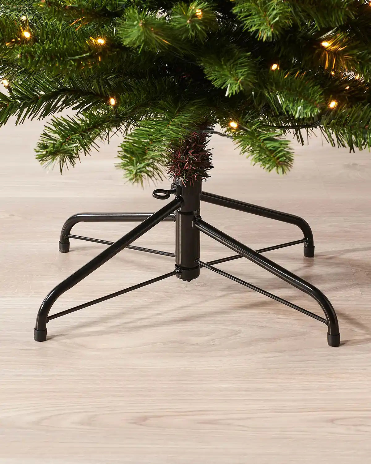 Close-up of the metal tree stand beneath a 6.5ft pre-lit green pencil Christmas tree