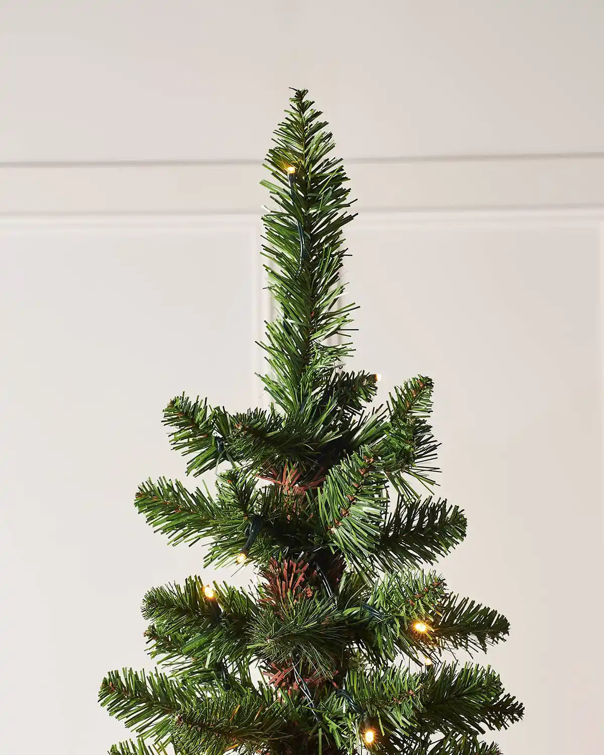Top section of a 6.5ft green pencil Christmas tree with warm white lights