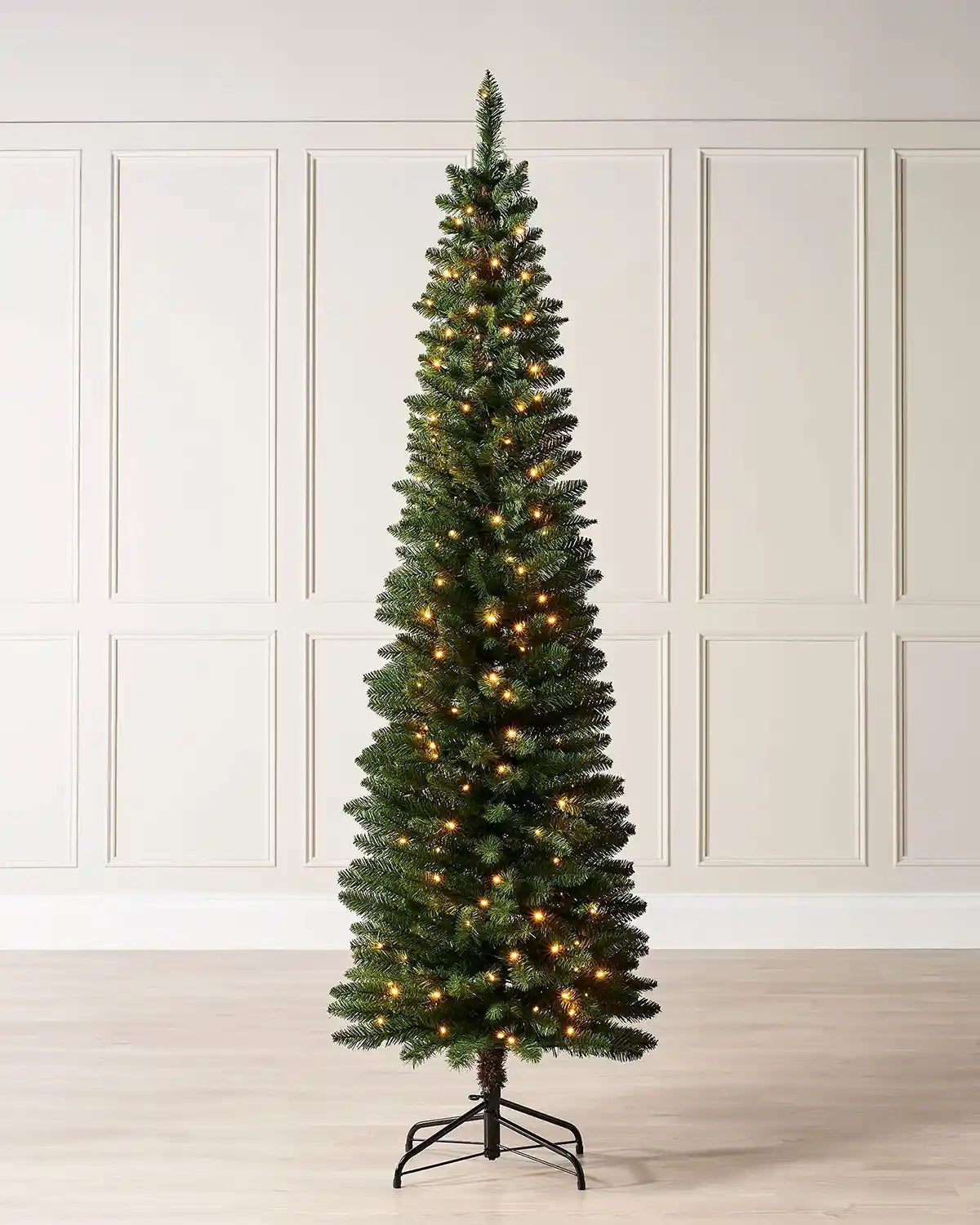 6.5ft green pencil Christmas tree displayed indoors with warm white lights and metal tree stand