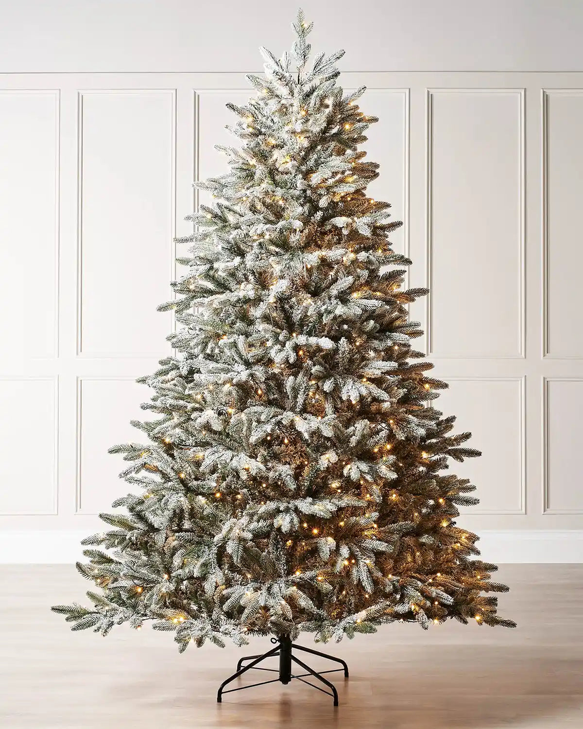 Pre-lit 6.5 ft snow flocked Christmas tree displayed indoors with warm white LEDs and a full frosted silhouette