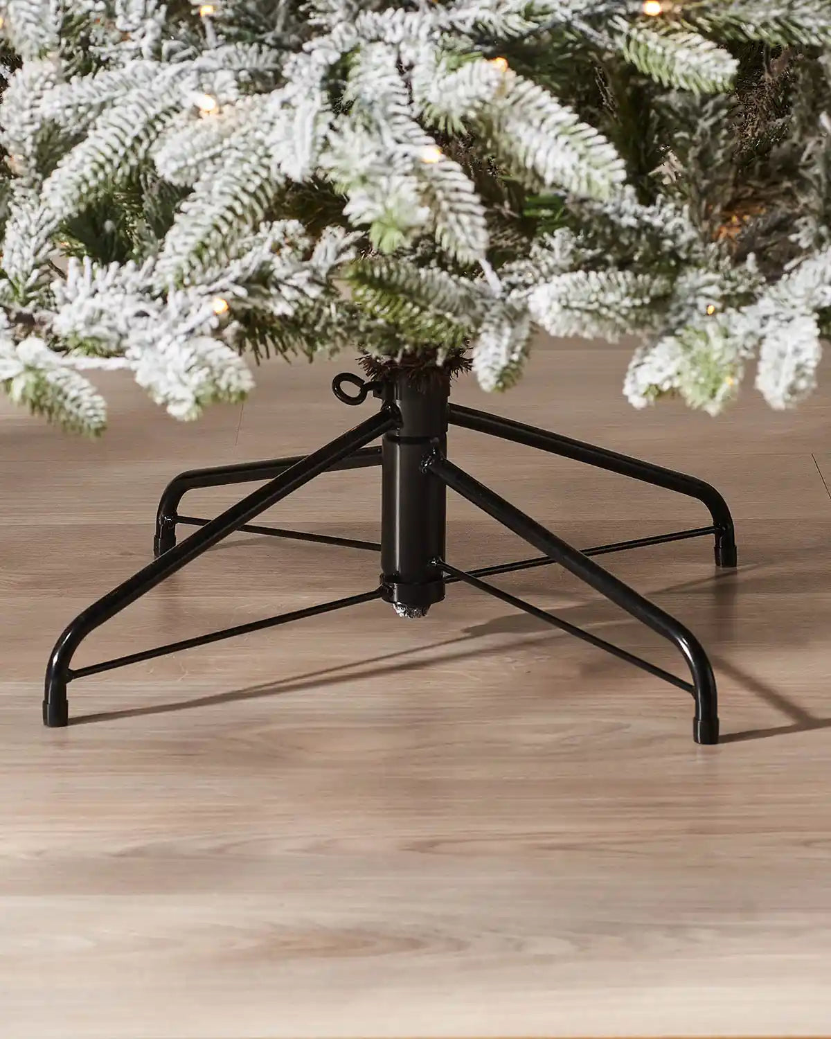 Close-up of the black metal stand on a 6.5 ft pre-lit snow flocked Christmas tree