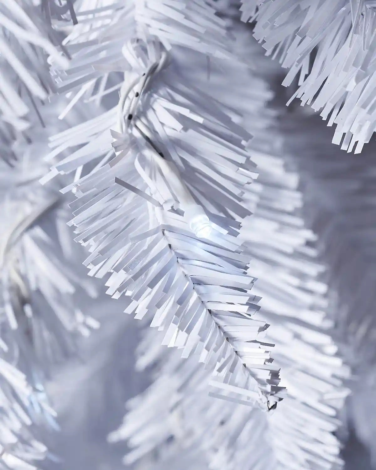 Close-up of a white LED light among white Christmas tree branches