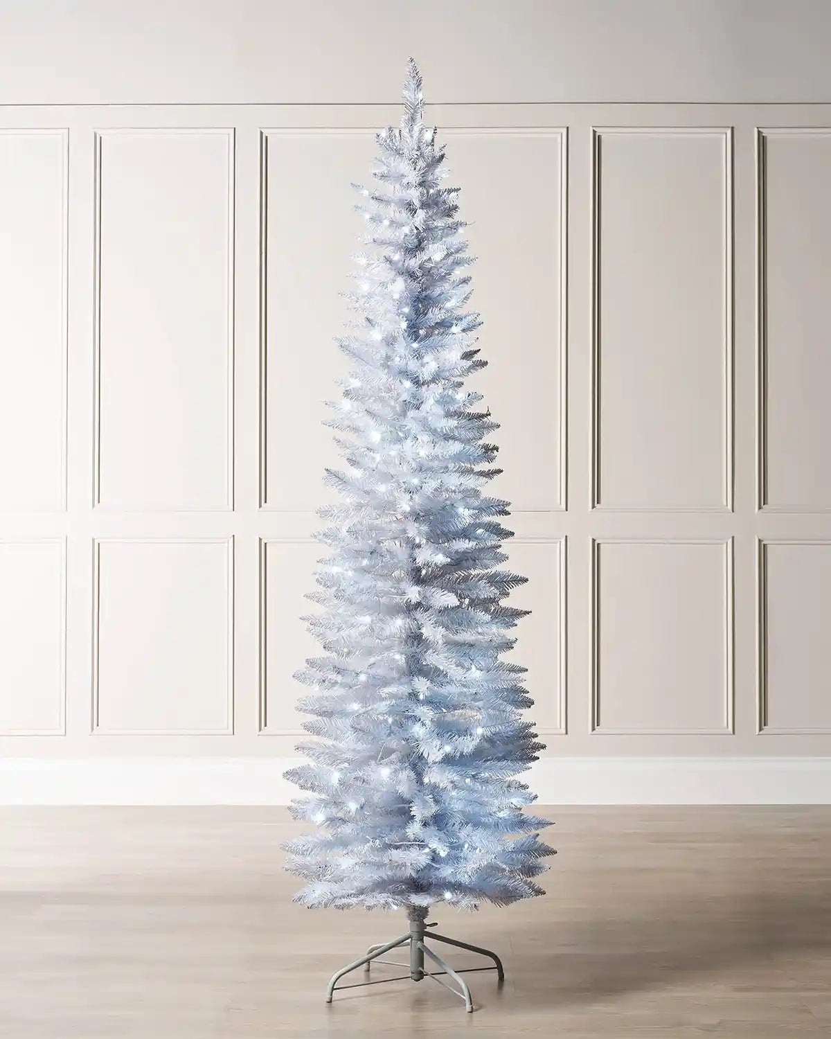 6.5ft white pencil Christmas tree displayed indoors with white LED lights and metal tree stand