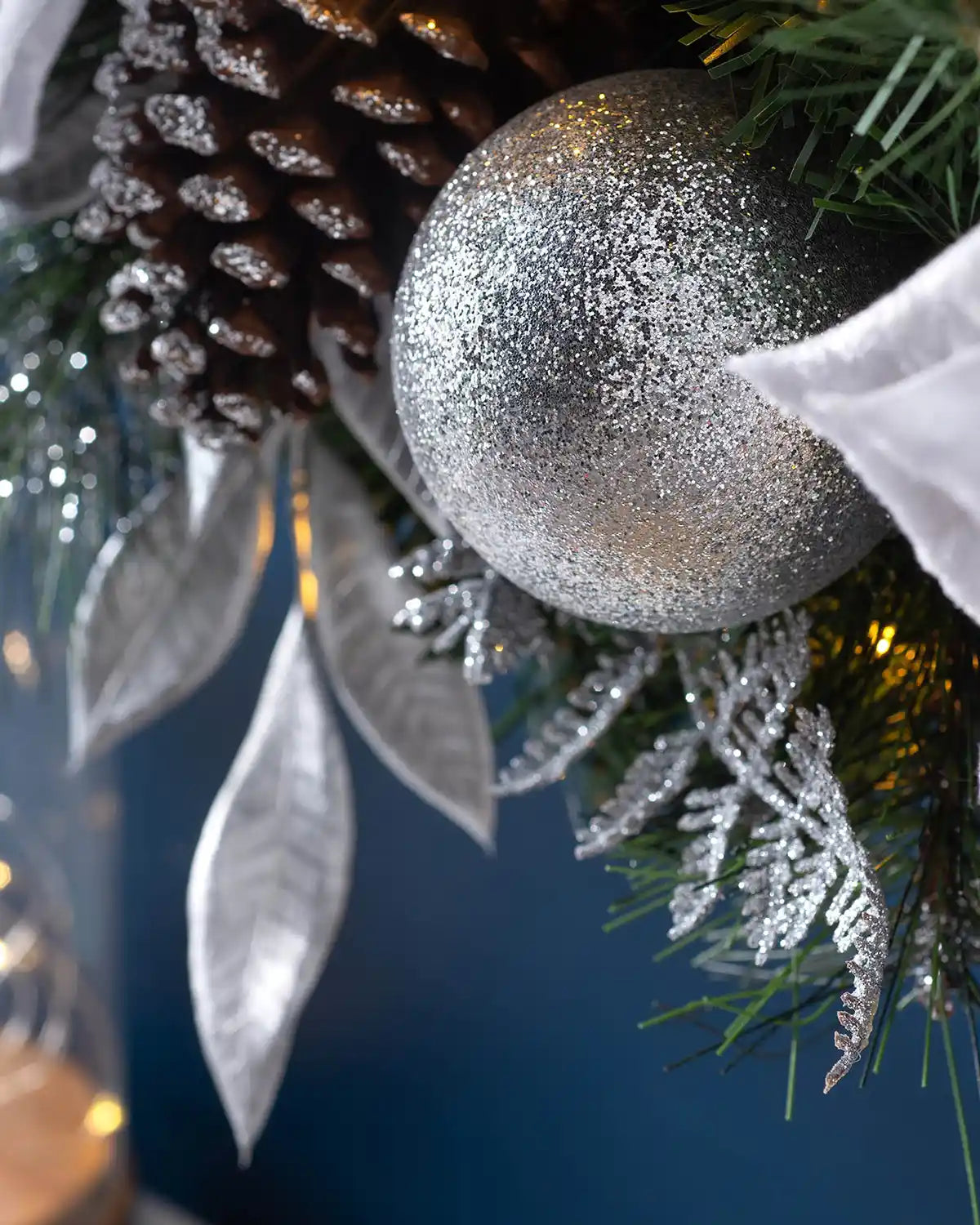 Detail of a silver bauble, frosted pinecone and silver leaves on the pre-lit Christmas wreath