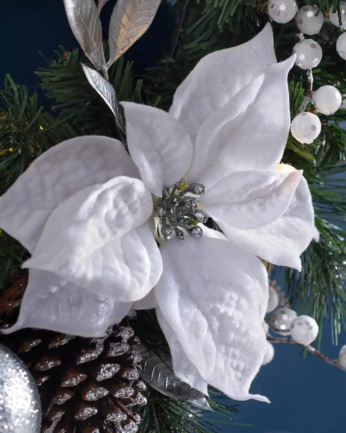 Close-up of a white poinsettia, berries and silver leaves on the pre-lit Christmas wreath