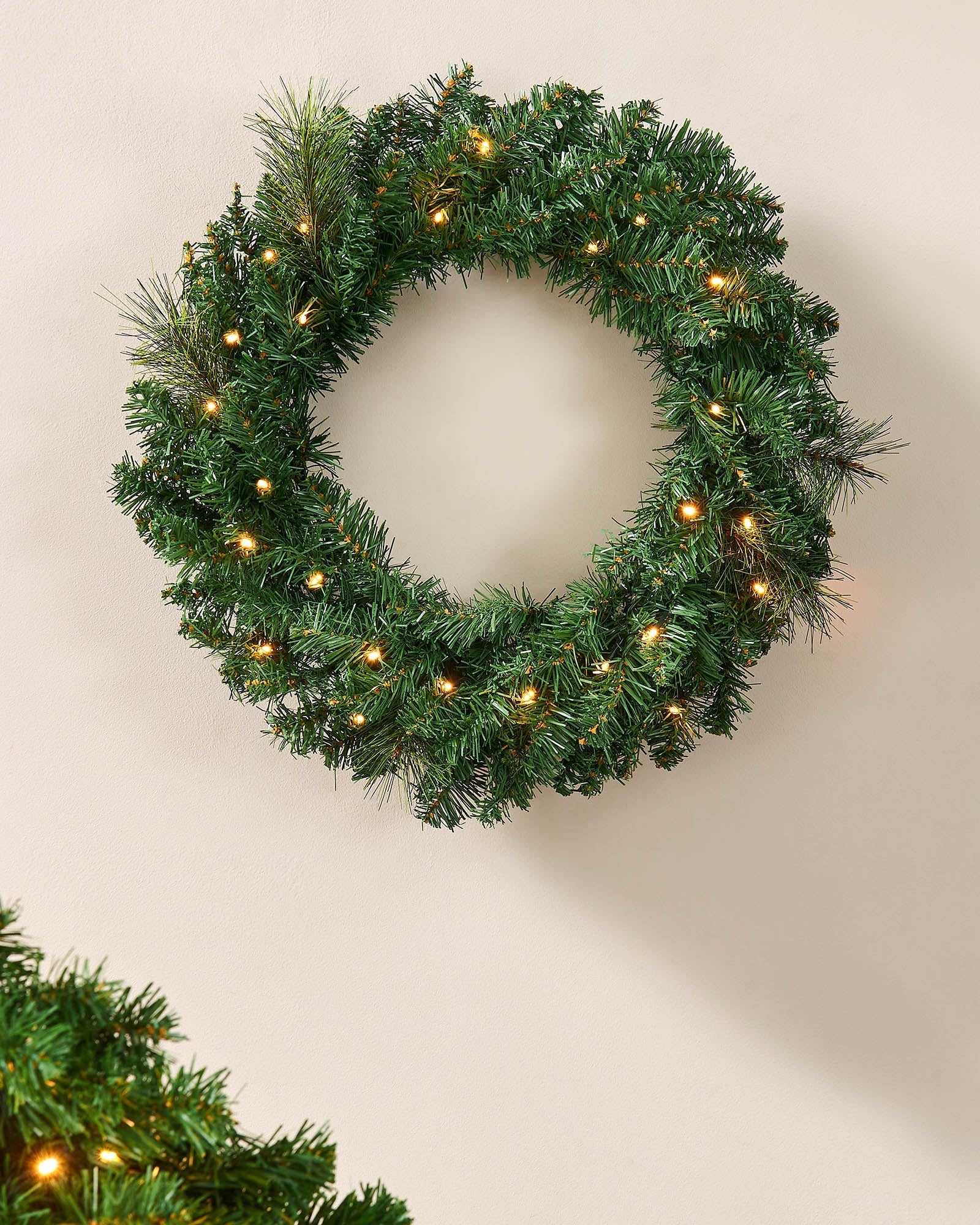 60 cm green pre-lit Christmas wreath with warm white LEDs displayed on a wall