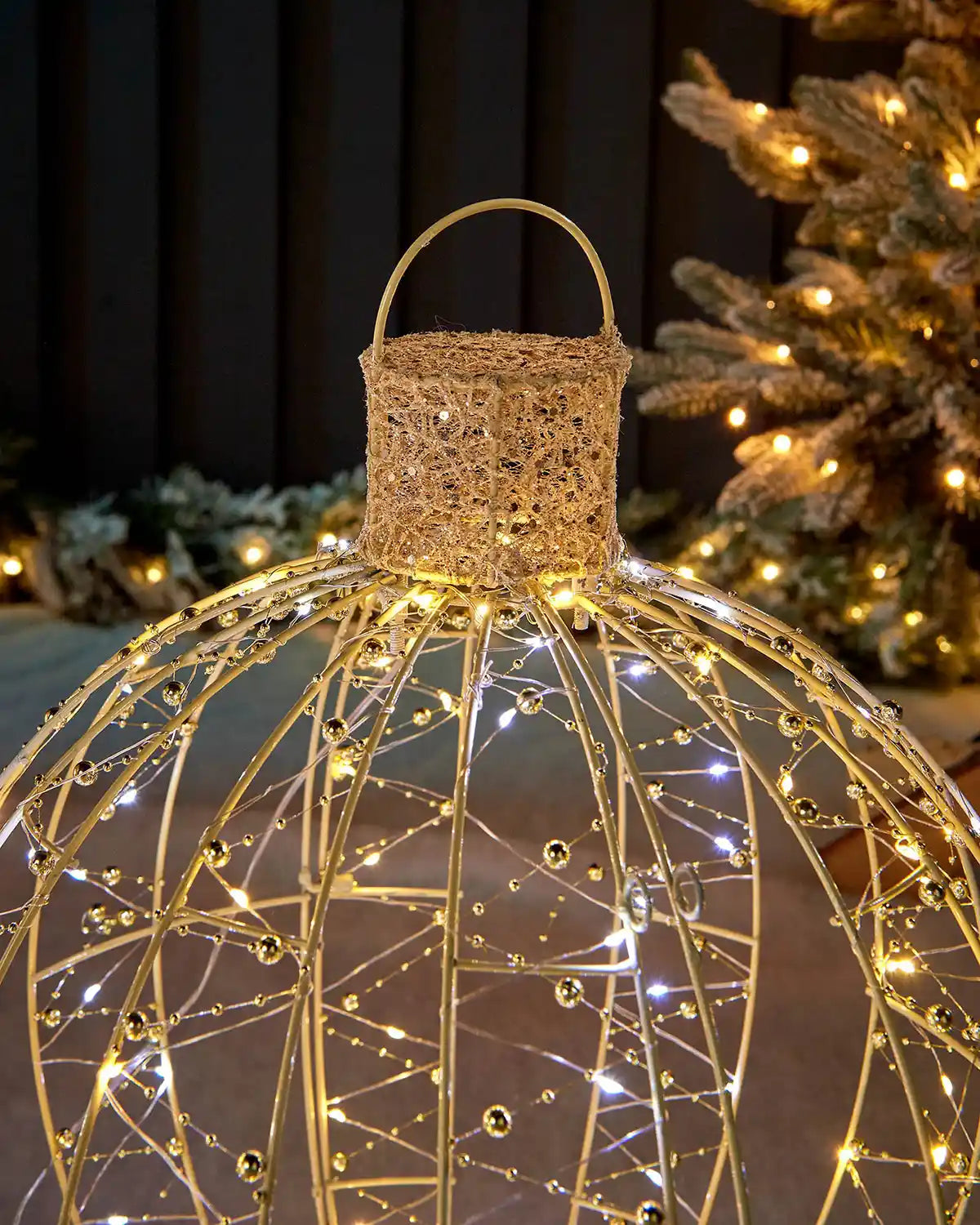 Close-up of the bauble silhouette cap and hanging loop with gold frame, beads and mixed white lights.