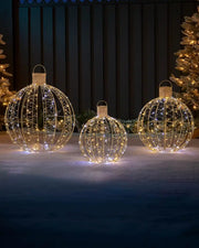 Set of three pre-lit gold bauble silhouettes displayed outdoors with warm and bright white lights.