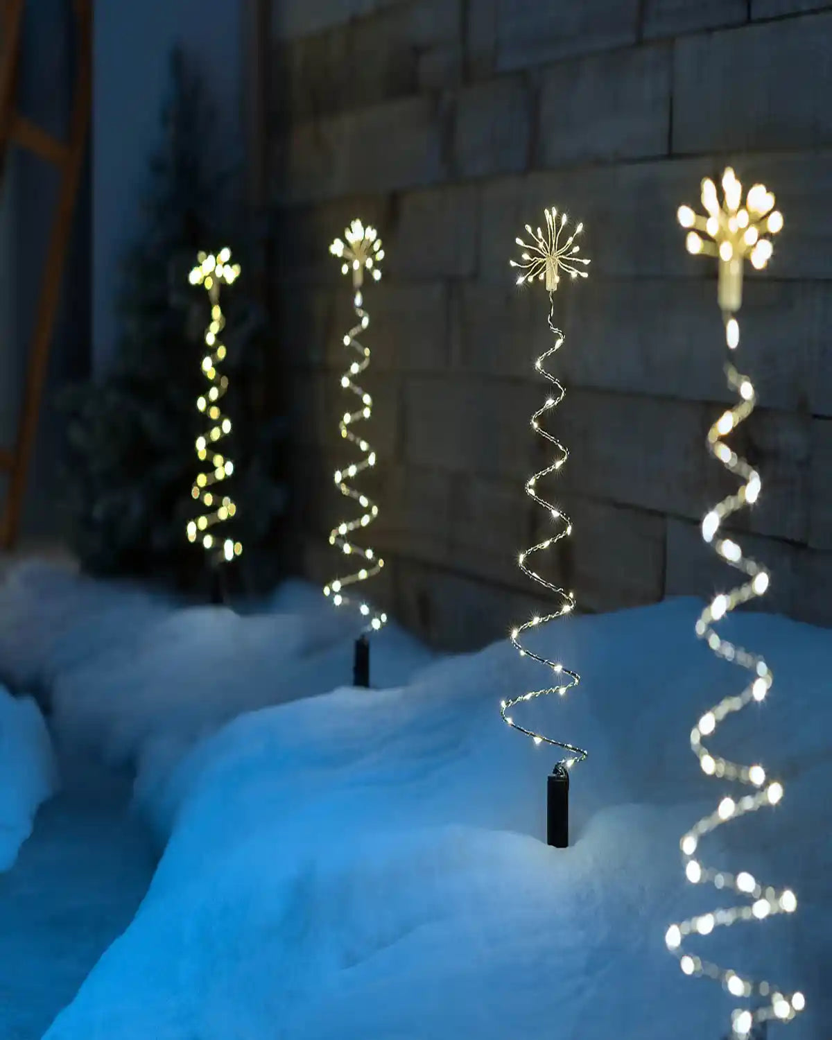Set of illuminated spiral firework pathway lights displayed along snowy pathway