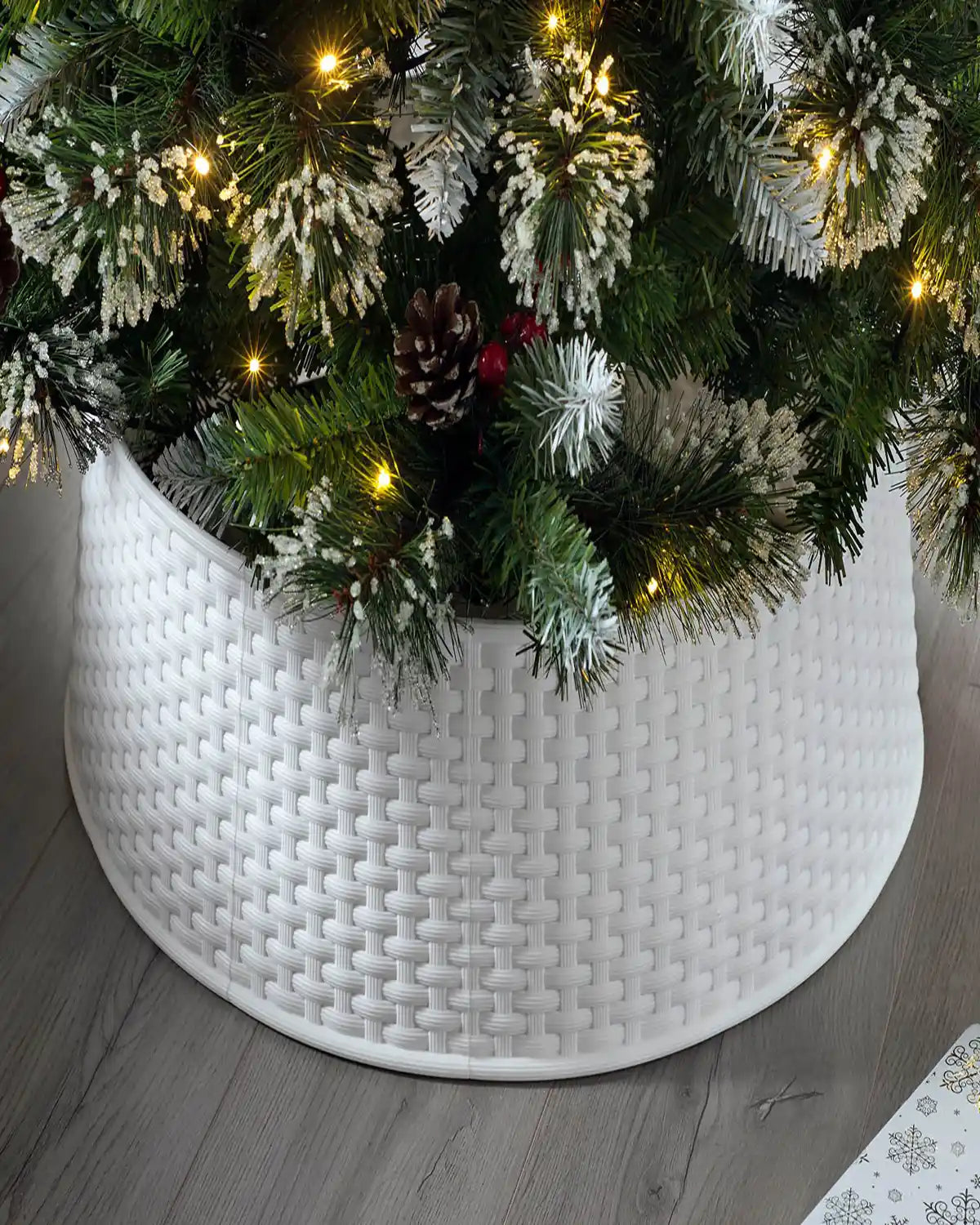 65 cm white rattan effect tree collar hiding the base of a decorated Christmas tree