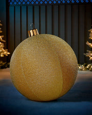 Large gold 66cm inflatable tinsel Christmas bauble with a gold cap in an outdoor festive display.