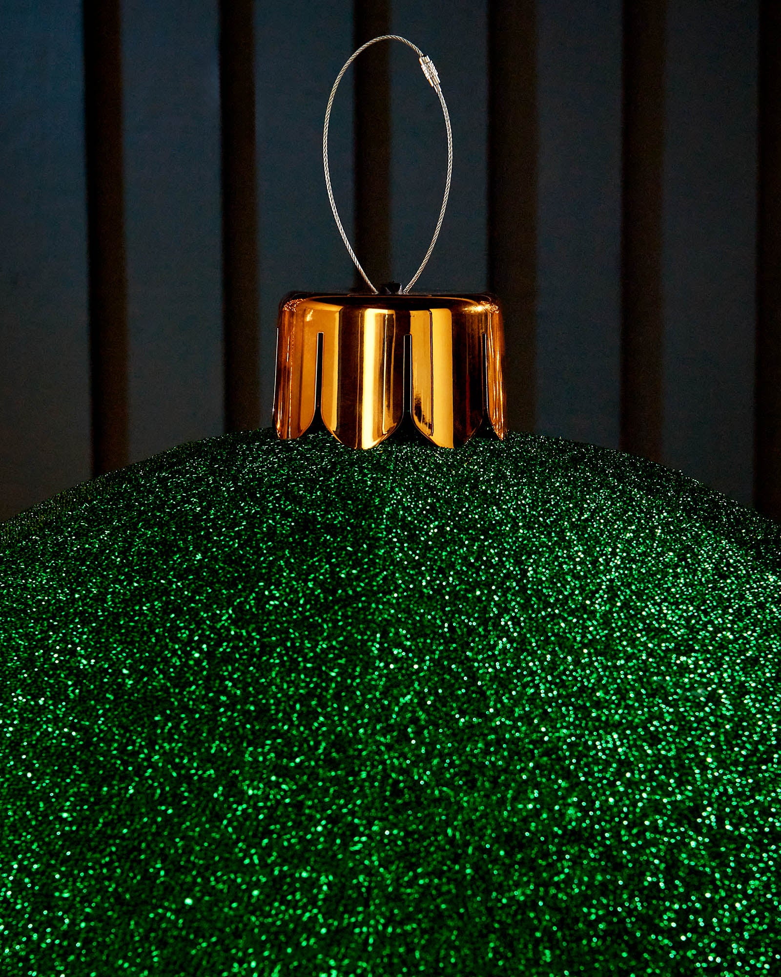 Close-up of the gold cap and hanging wire on a green inflatable tinsel Christmas bauble.