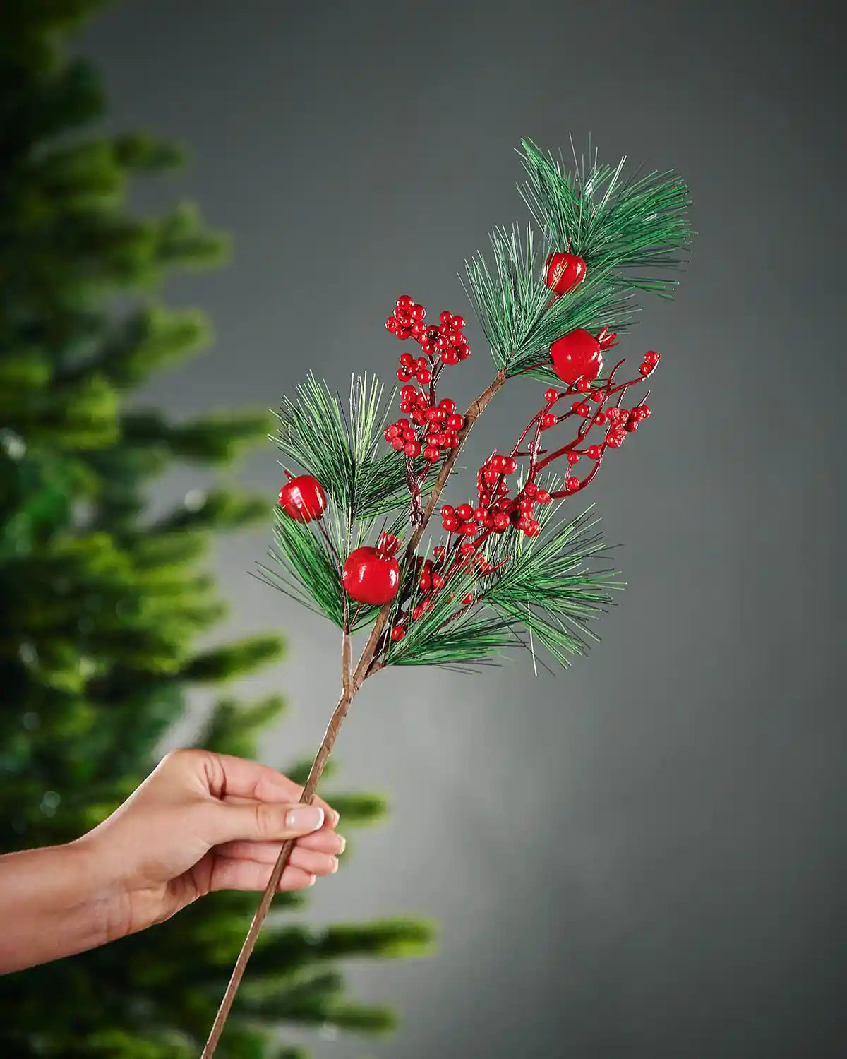 66 cm red artificial berries tree pick held beside a Christmas tree