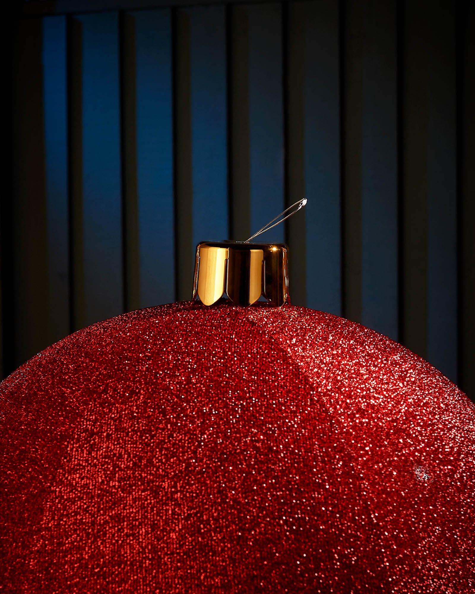 Close-up of the gold cap and hanging wire on a red 66cm inflatable tinsel Christmas bauble.