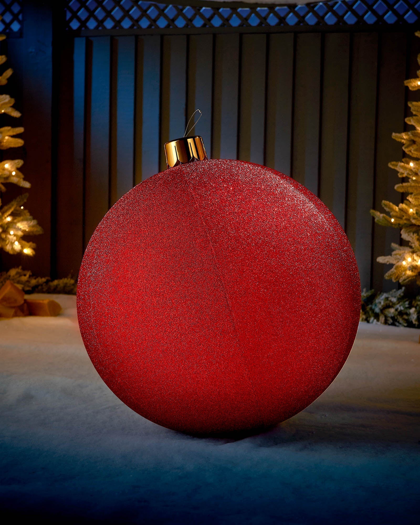 Large red 66cm inflatable tinsel Christmas bauble with a gold cap in an outdoor festive display.