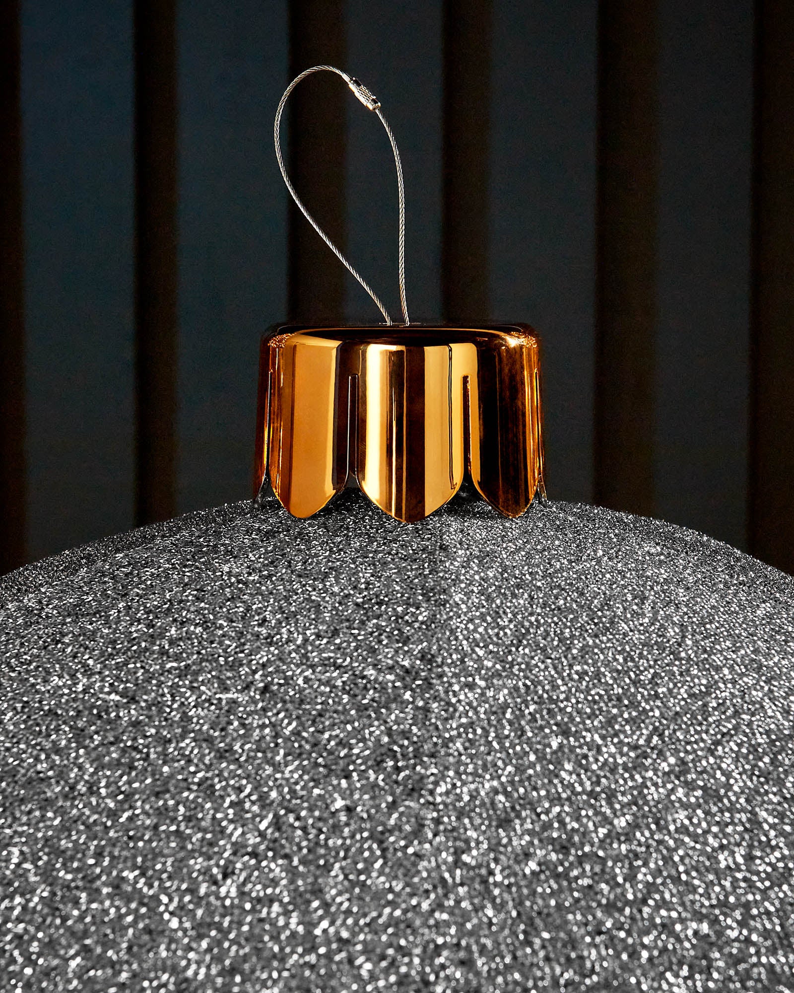 Close-up of the gold cap and hanging wire on a silver 66cm inflatable tinsel Christmas bauble.