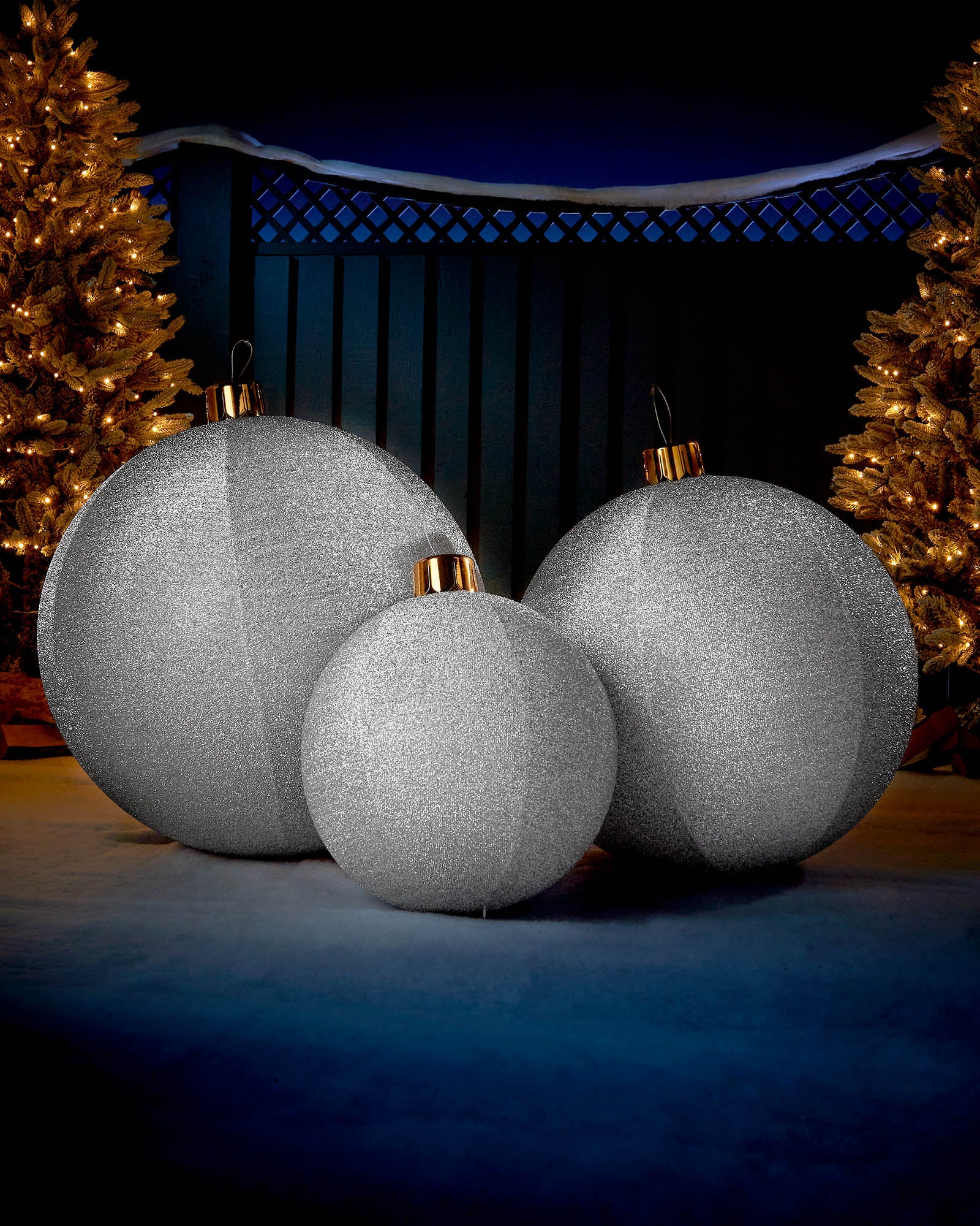 Silver 66cm inflatable tinsel Christmas baubles displayed outdoors with warm festive lights.
