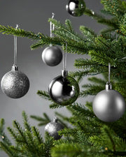 6 Silver  Christmas baubles on a tree against a grey background