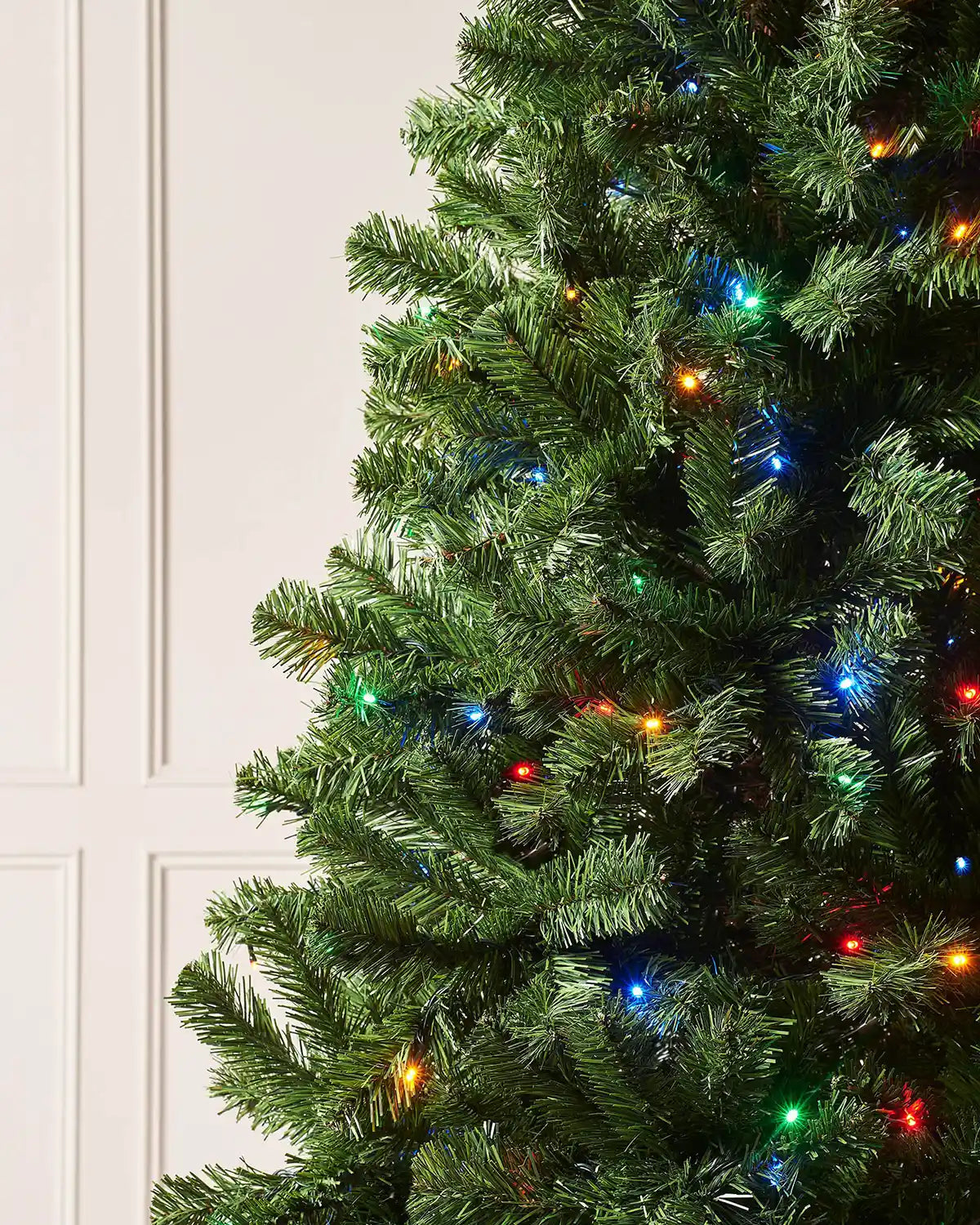 Close-up of green PVC branches on a 6 ft emerald spruce tree with multi-coloured LED lights