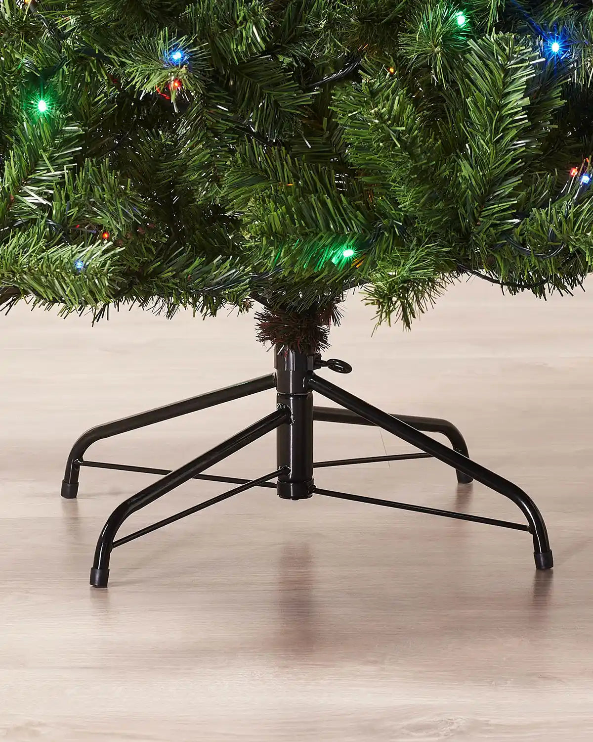 Close-up of the metal tree stand beneath a 6 ft pre-lit emerald spruce Christmas tree