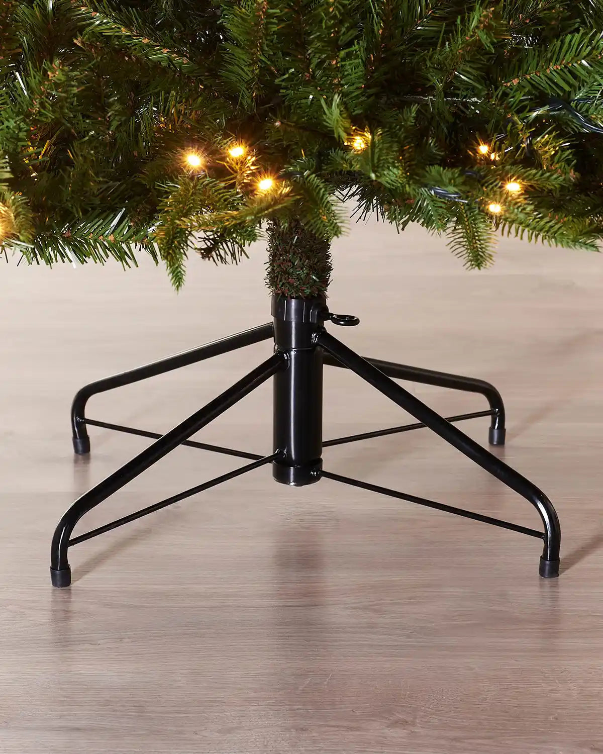 Close-up of the lower branches, warm white lights and metal tree stand on a 6ft Royal Fir Christmas tree