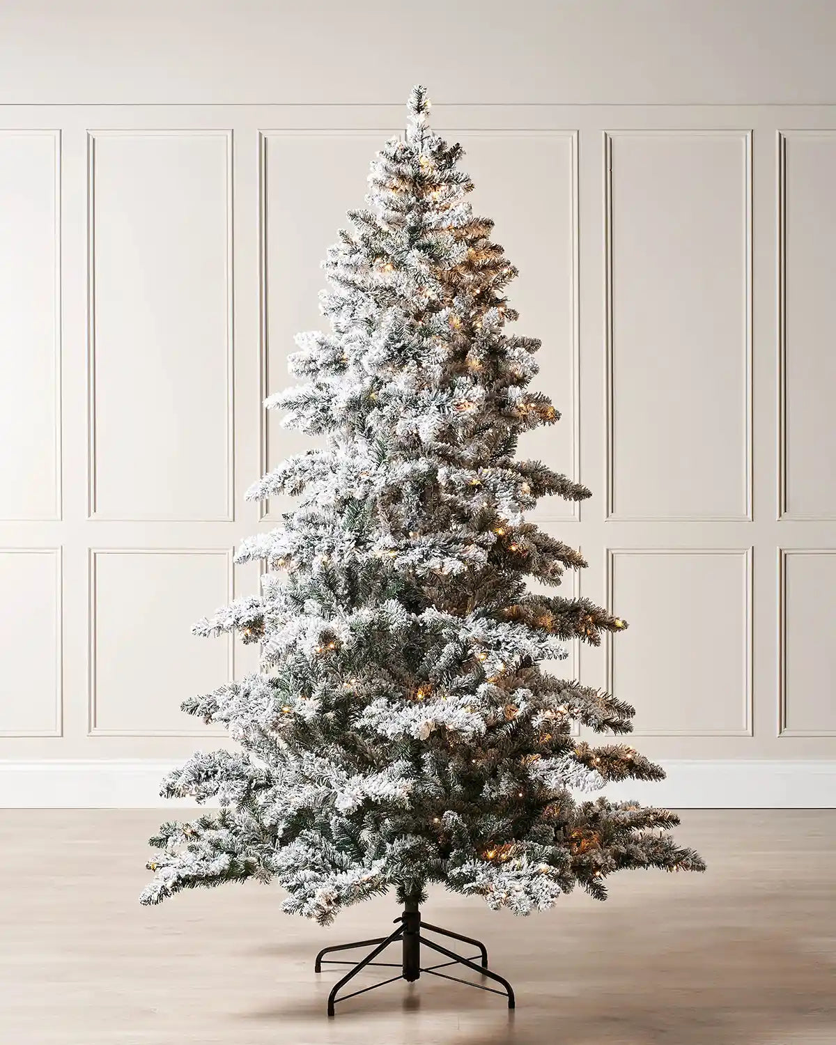 6 ft pre-lit snow flocked Alpine Christmas tree with warm white lights and a black metal tree stand.