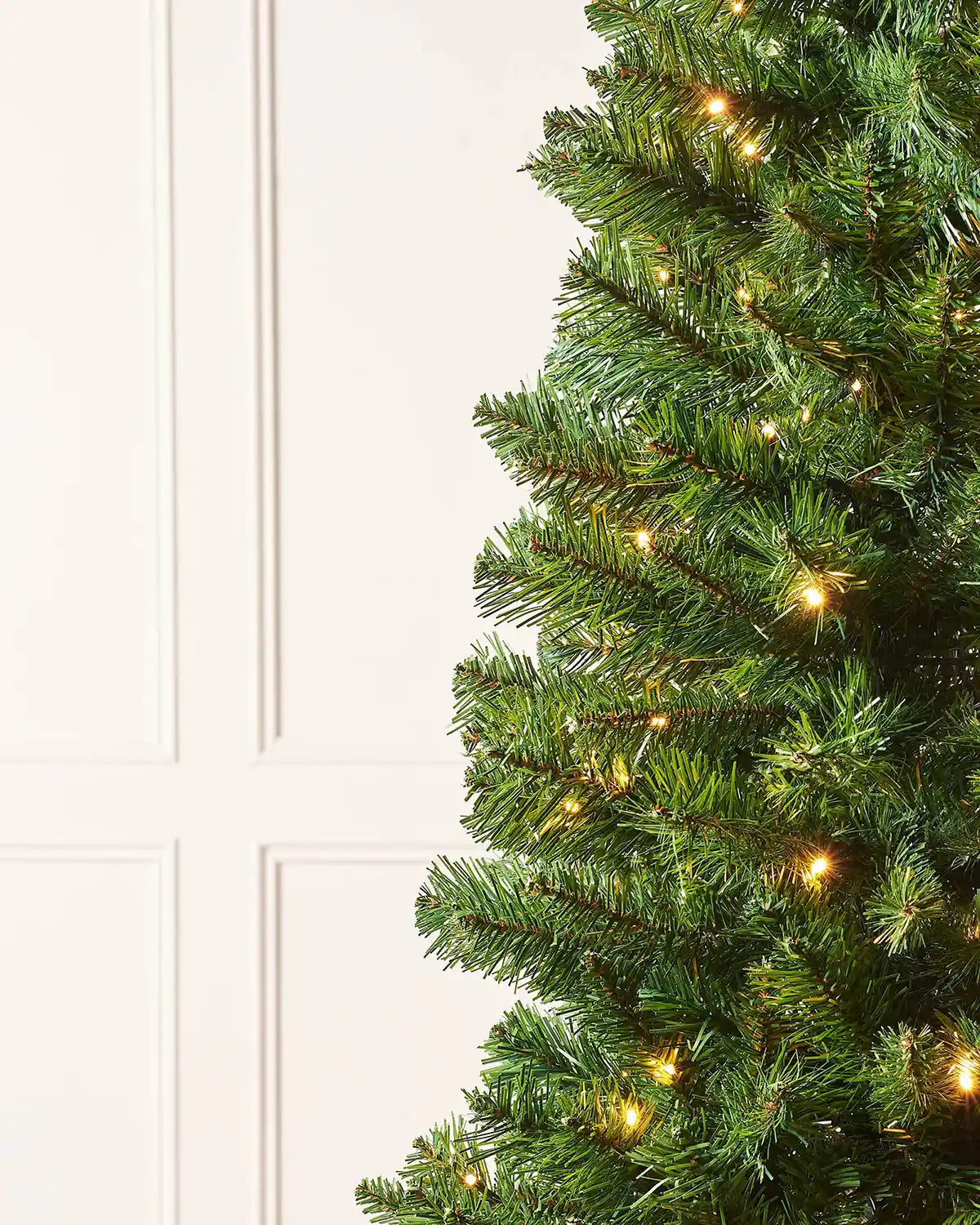 Close-up of 6ft slim Christmas tree branches with warm white LEDs and green foliage