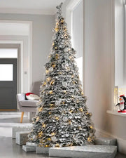 Snow flocked pop-up Christmas tree with warm white lights displayed indoors