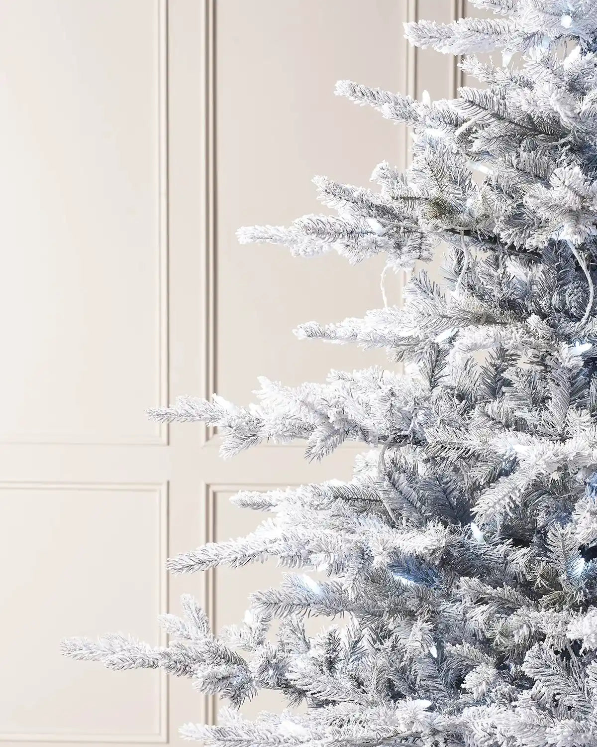 Close-up of 6ft snow flocked spruce Christmas tree branches with cool white LEDs and frosted foliage
