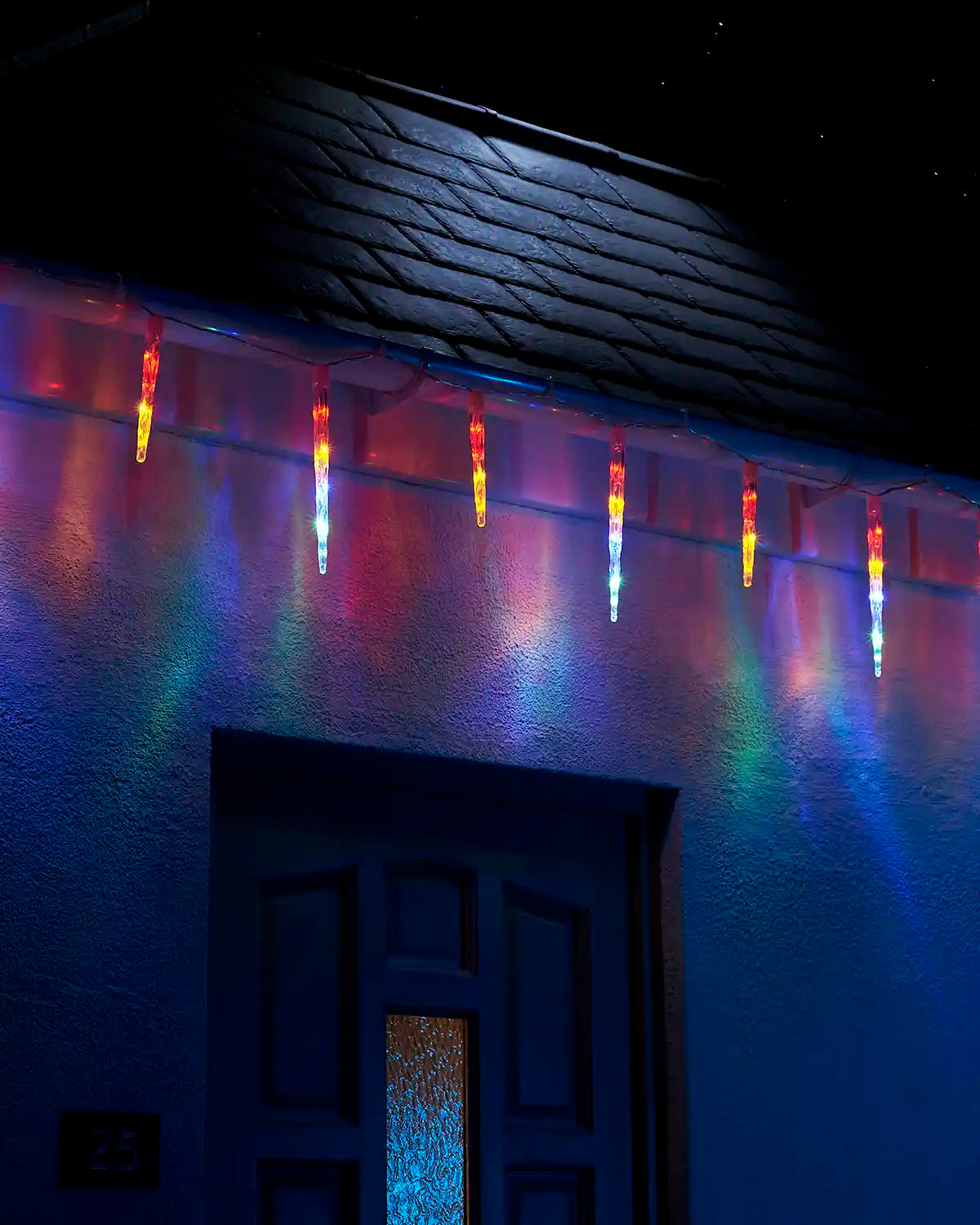 Multi-colour icicle drop lights hanging above a front door at night.