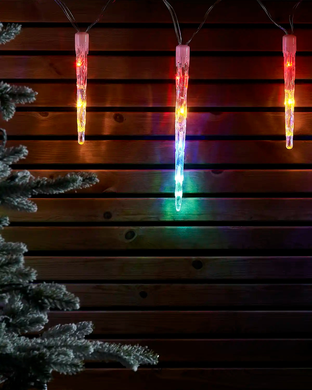 Multi-colour icicle drop lights displayed against a dark wooden wall.