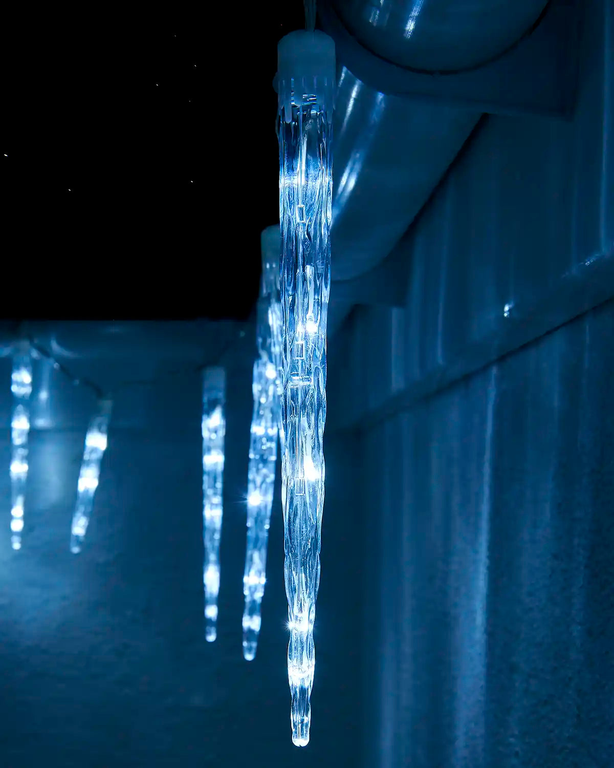 Close-up of a white LED icicle drop light hanging from a roofline.